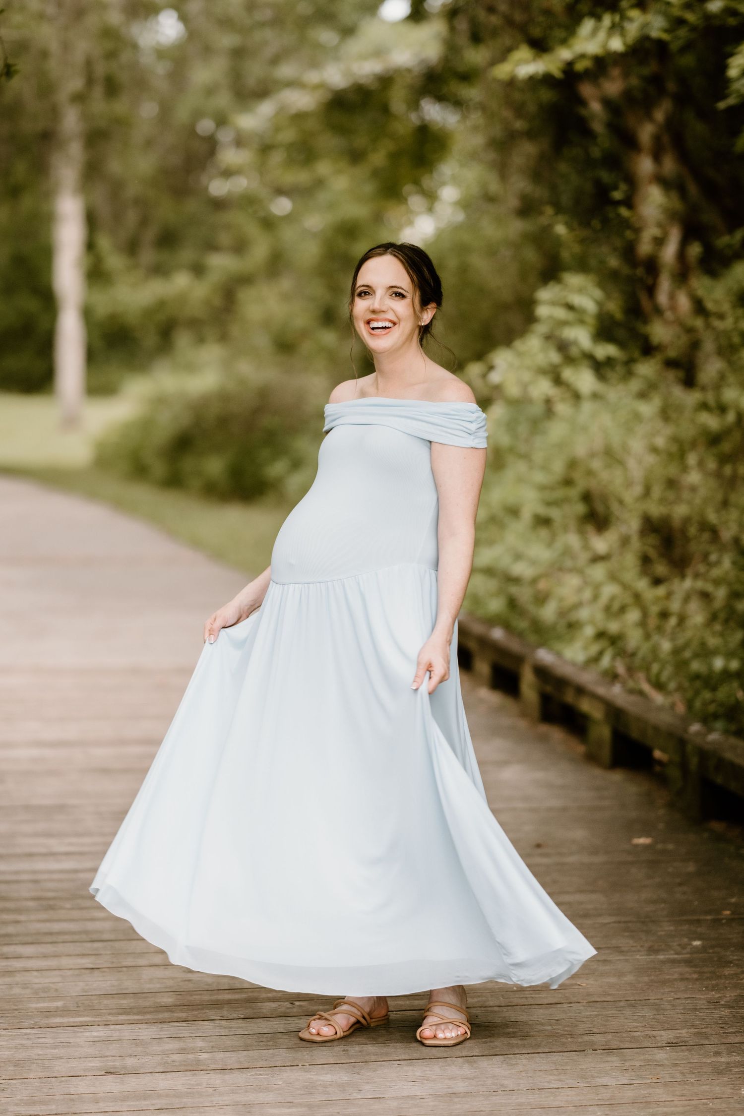 An ethereal light blue dress flows and spins on a rustic wooden pathway in a garden setting.