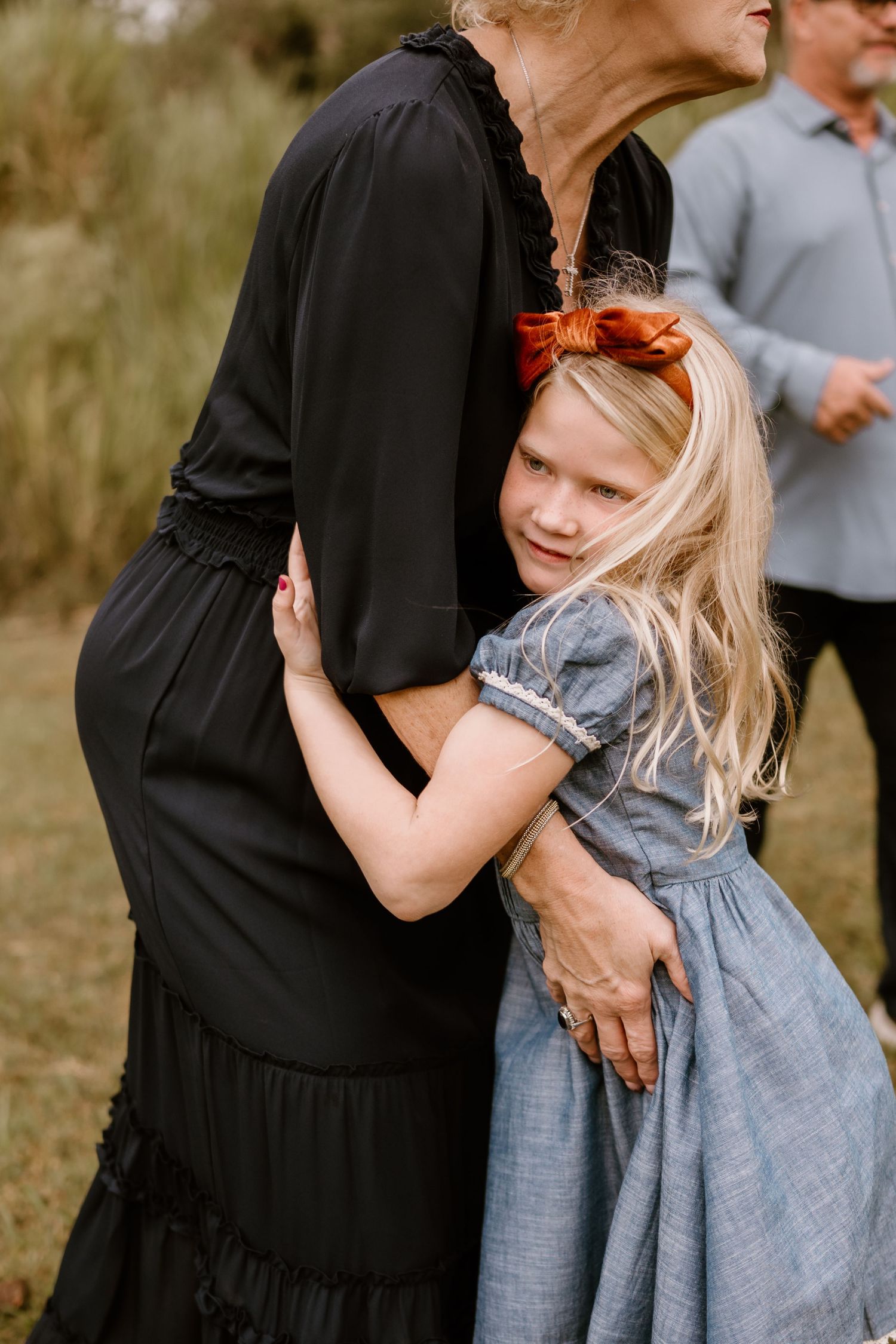 A touching moment captured between two people in casual attire against a natural backdrop.