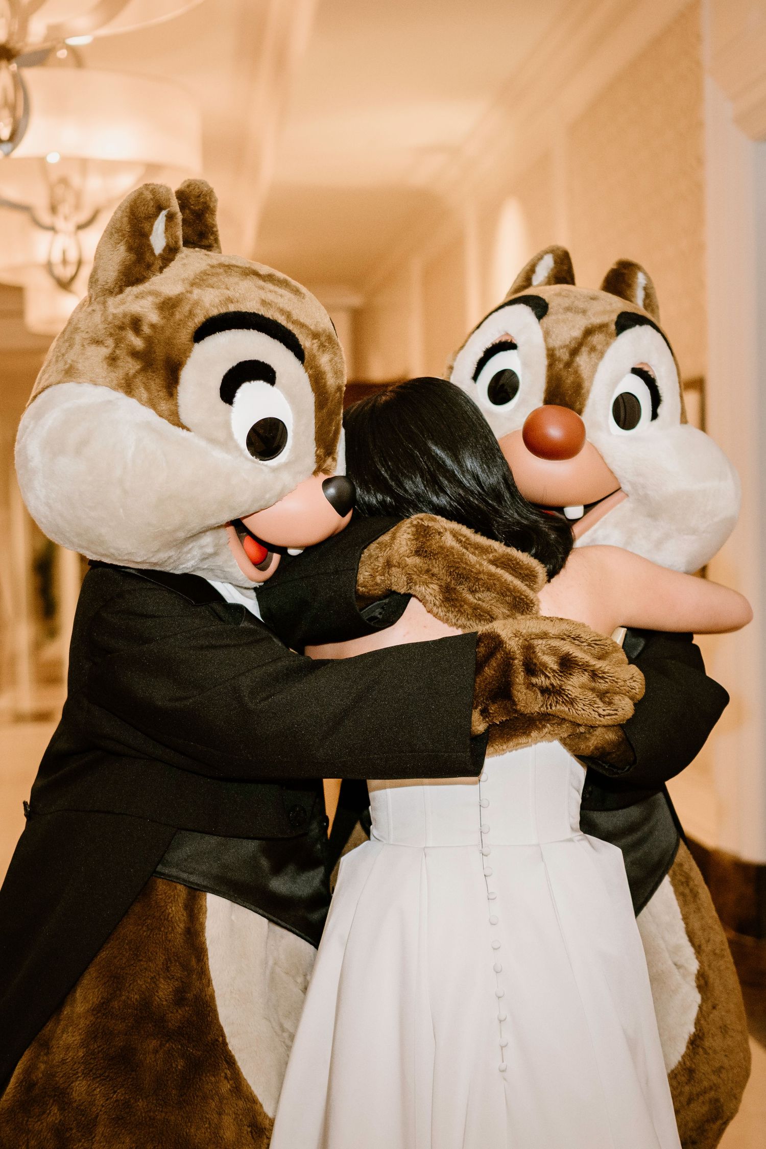 Chip and Dale Disney characters dance with a bride in formal wedding attire.