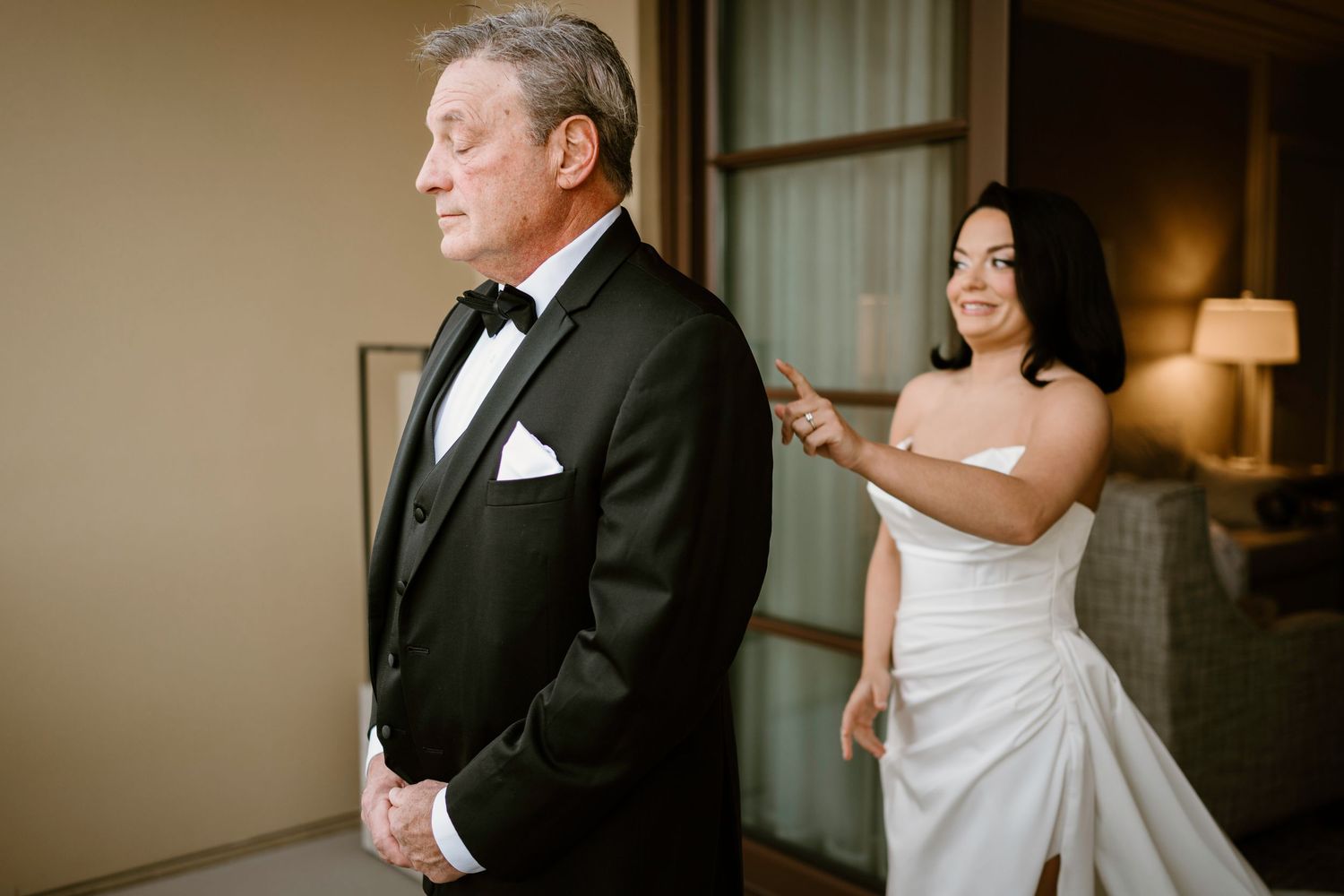 Emotional first look sequence between bride in white dress and man in tuxedo at wedding venue.