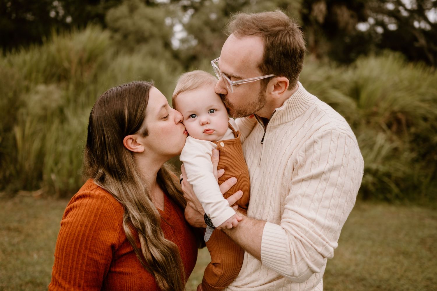 Family photo session in a natural outdoor setting wearing earth tones and casual clothing.