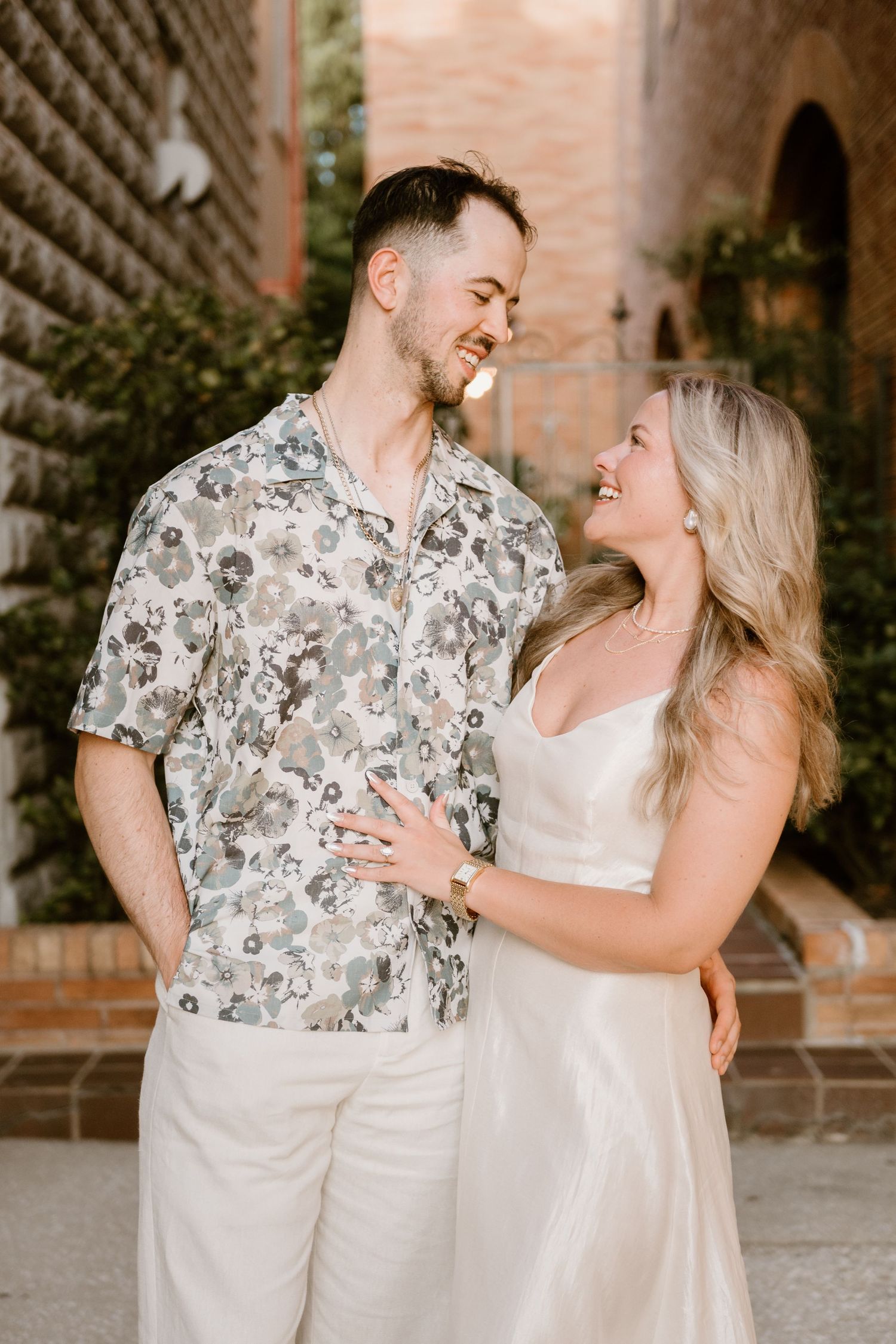 Happy couple in light summer attire sharing loving moments in a Mediterranean-style passageway.