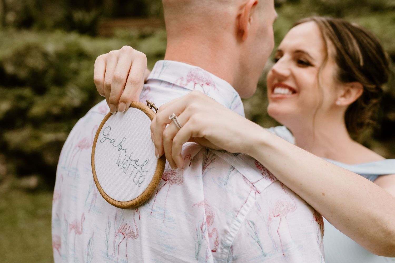 A couple shares a tender moment with embroidery hoop during outdoor photoshoot.