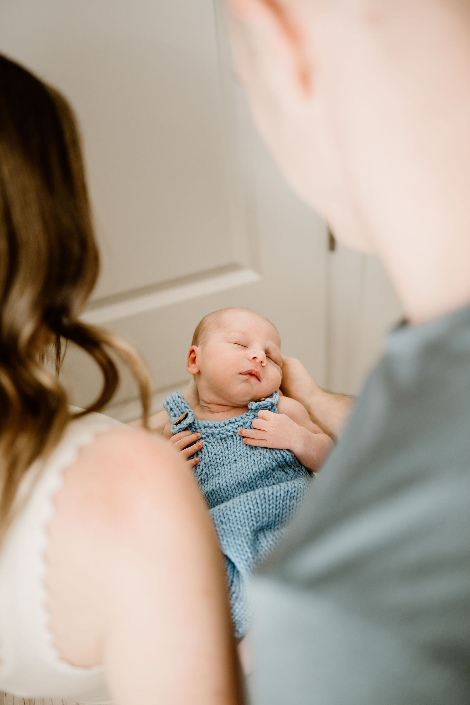 Soft focus portrait of a sleeping infant in a blue knitted outfit.