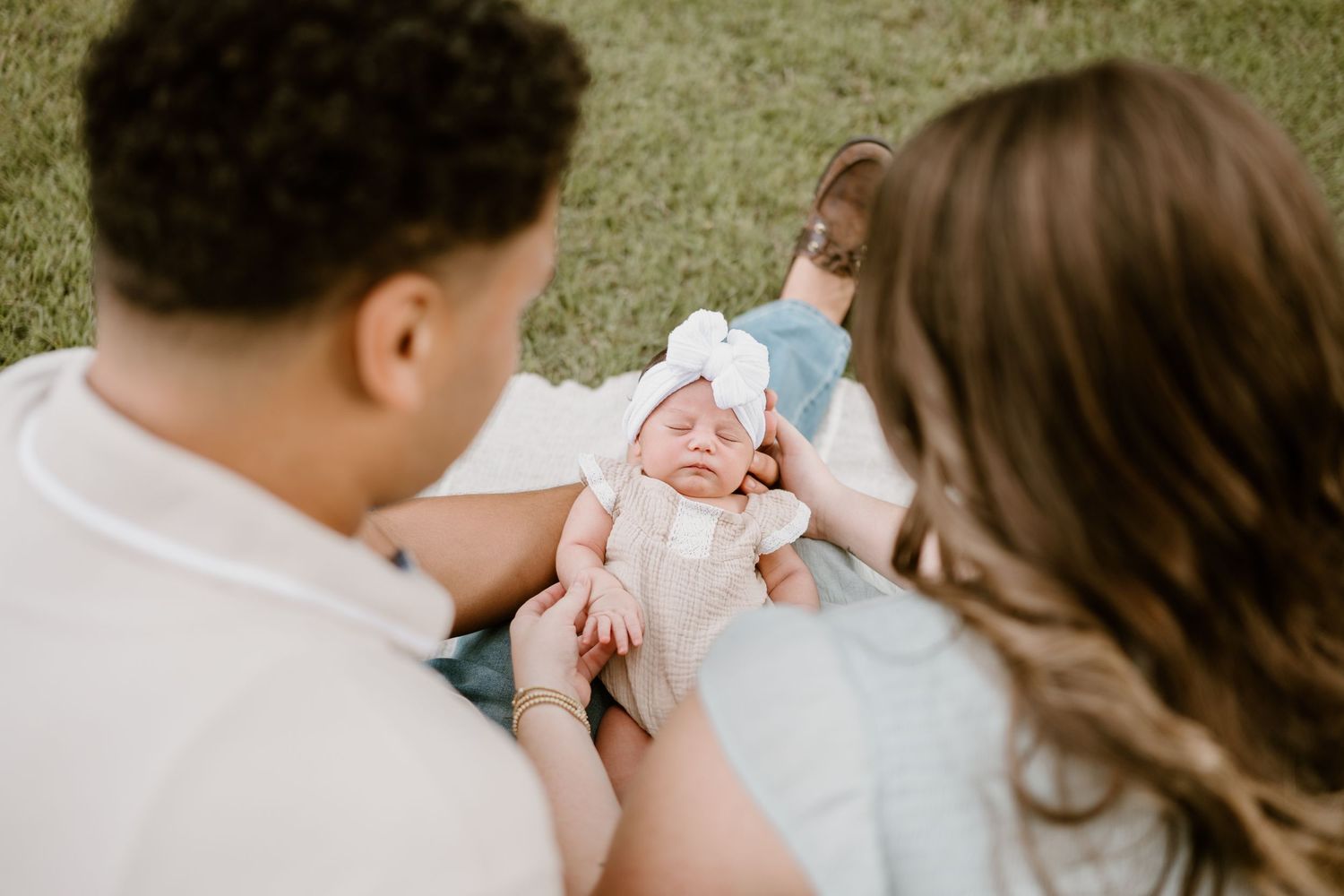 Intimate family portrait with a newborn baby being cradled outdoors.