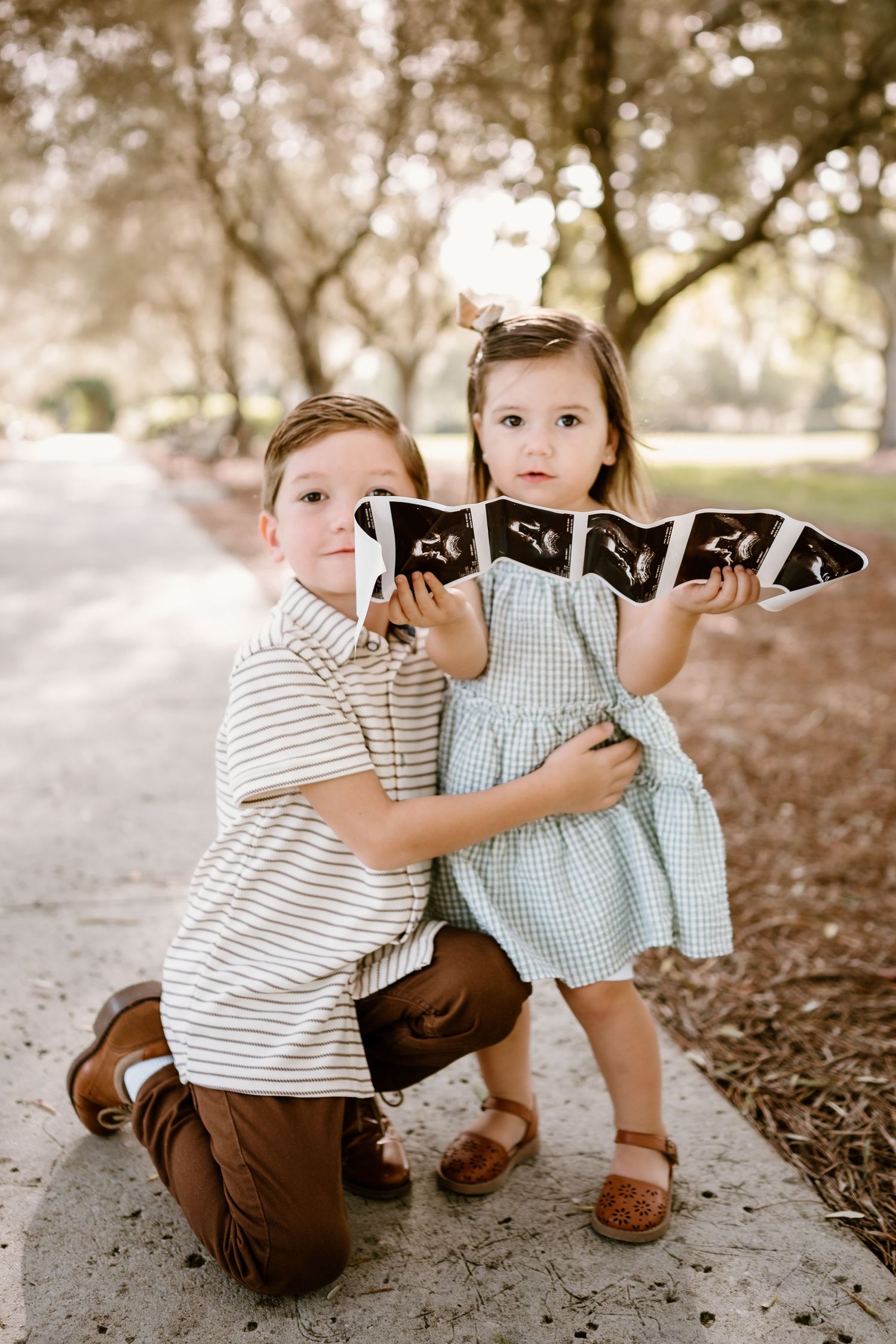 Two small children in coordinated outfits playing together on the ground.