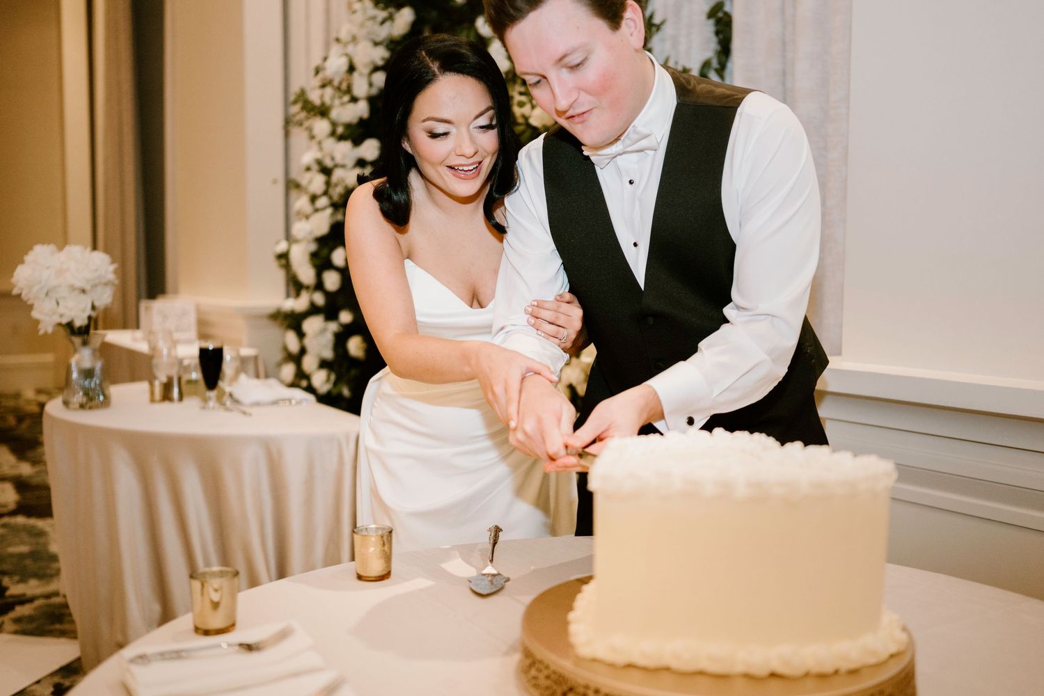 Newlyweds cut their wedding cake together at an elegant reception.
