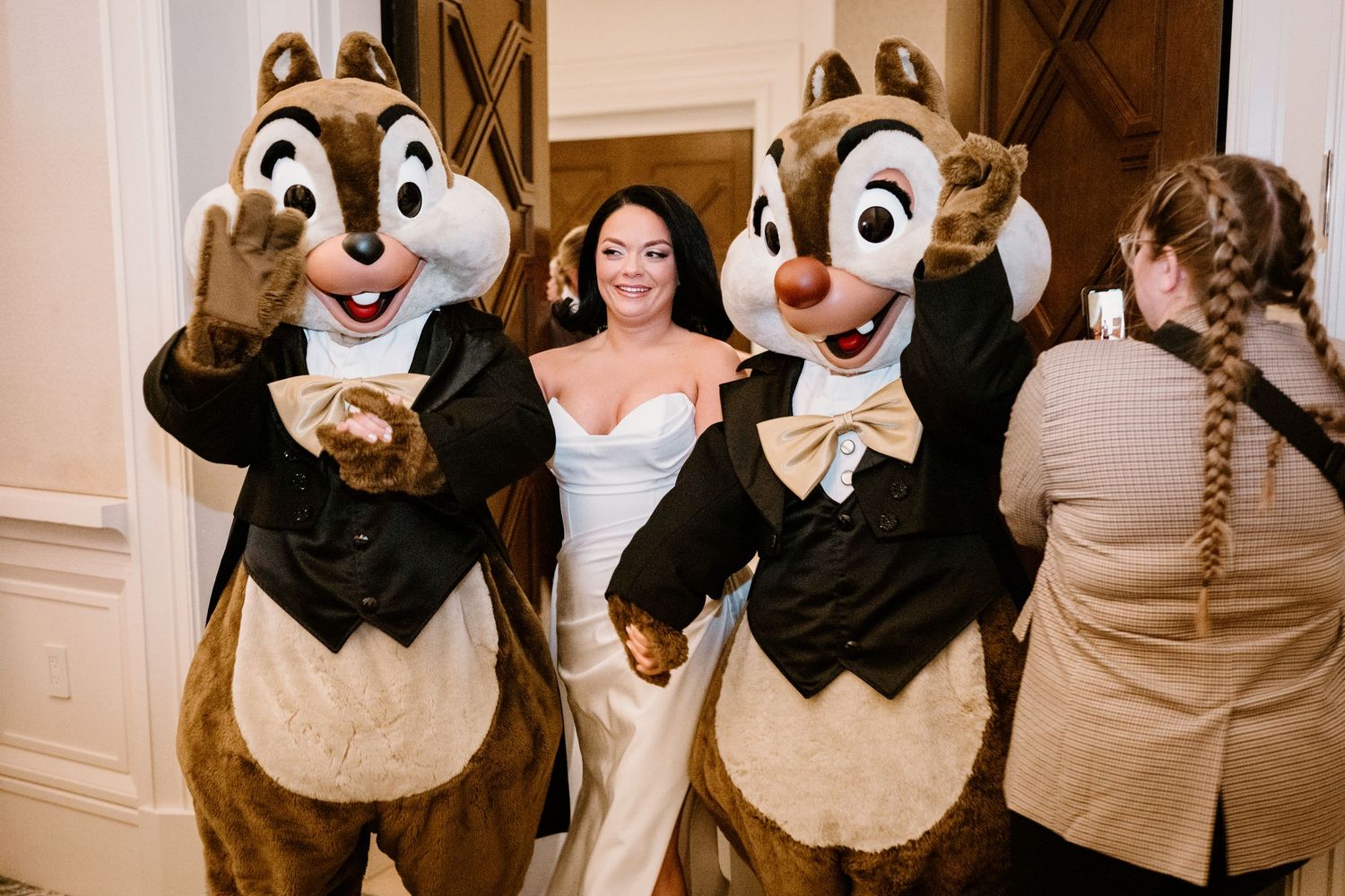 Chip and Dale Disney characters pose with a bride in a white gown at an elegant reception.