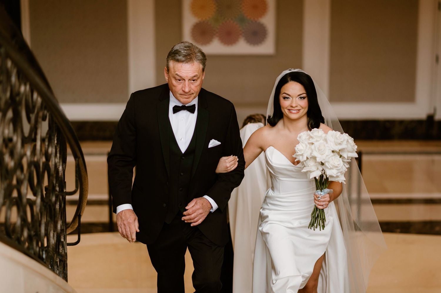 Formal wedding party walking down grand staircase during ceremony.