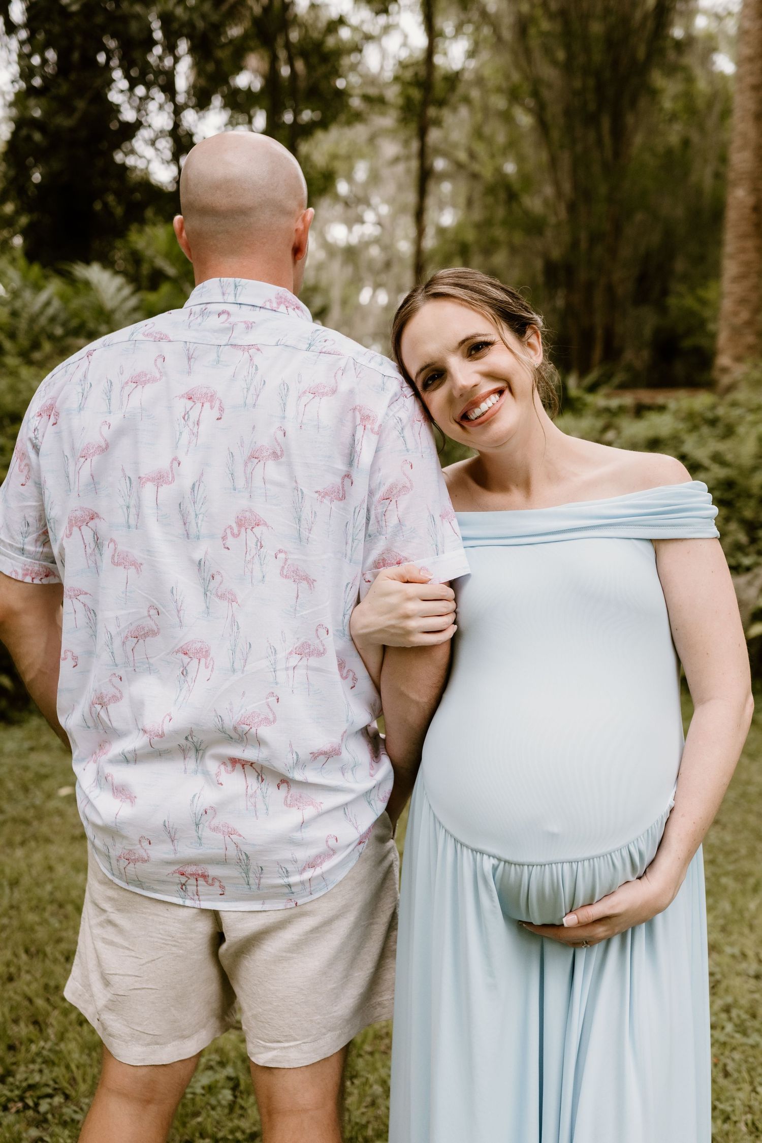 Couple sharing intimate moments during maternity photoshoot in natural outdoor setting.