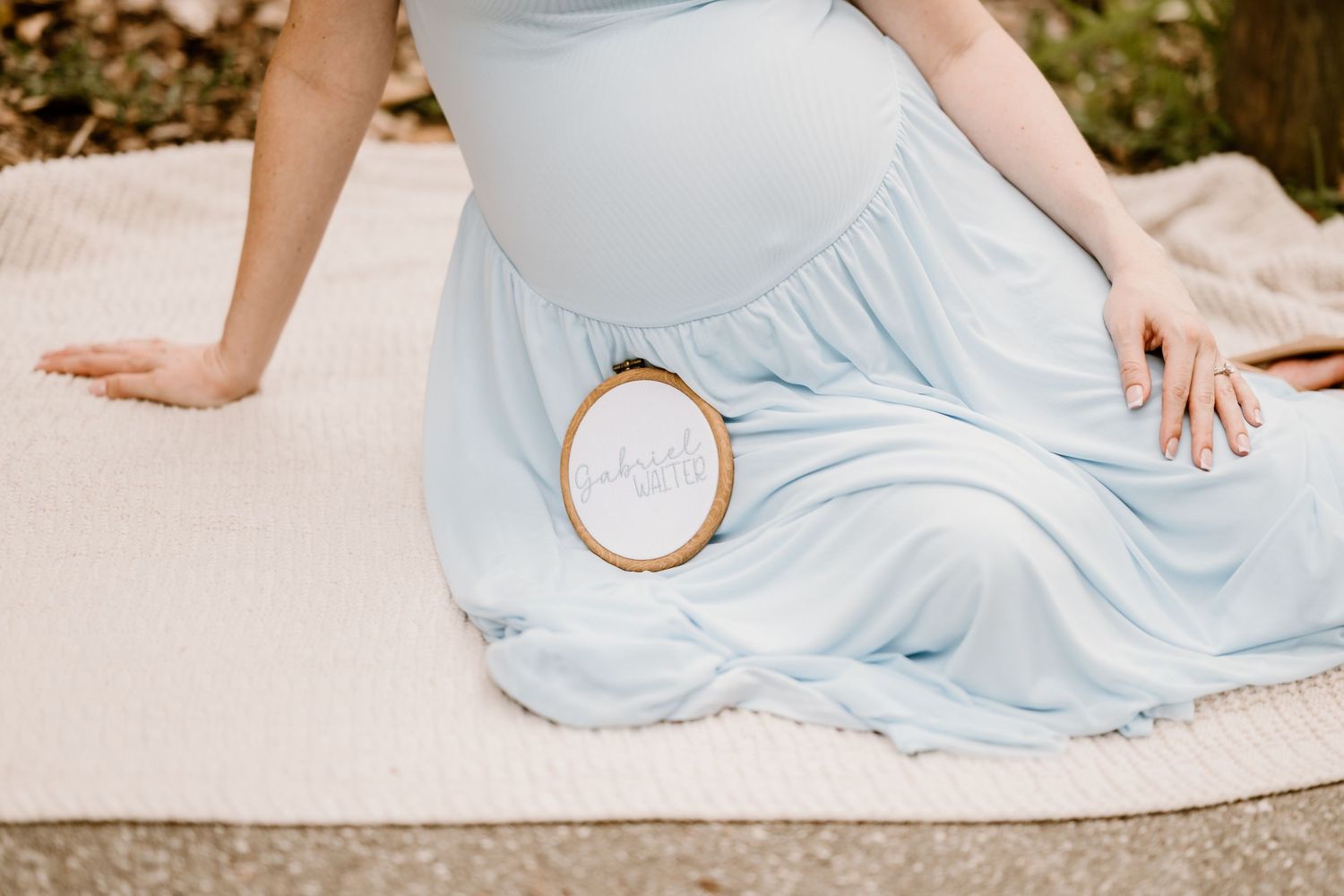 Light blue maternity dress detail shot on sandy beach during sunset.