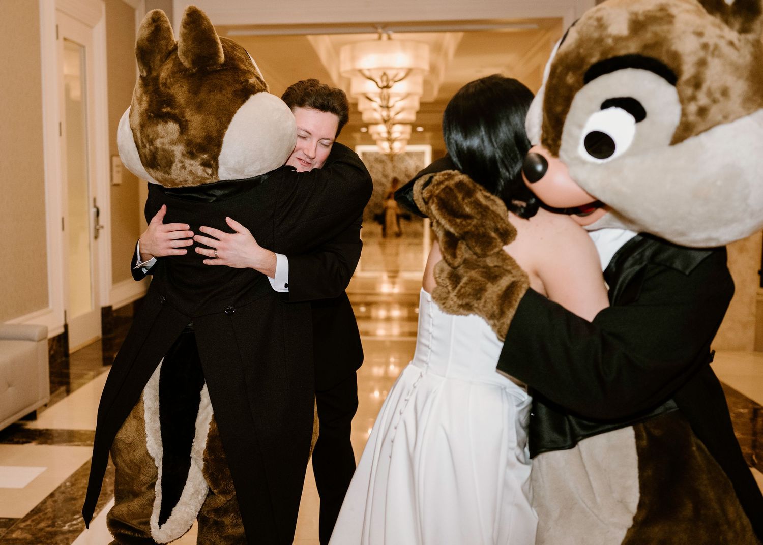 Wedding party dances with Disney character mascots in elegant ballroom setting.