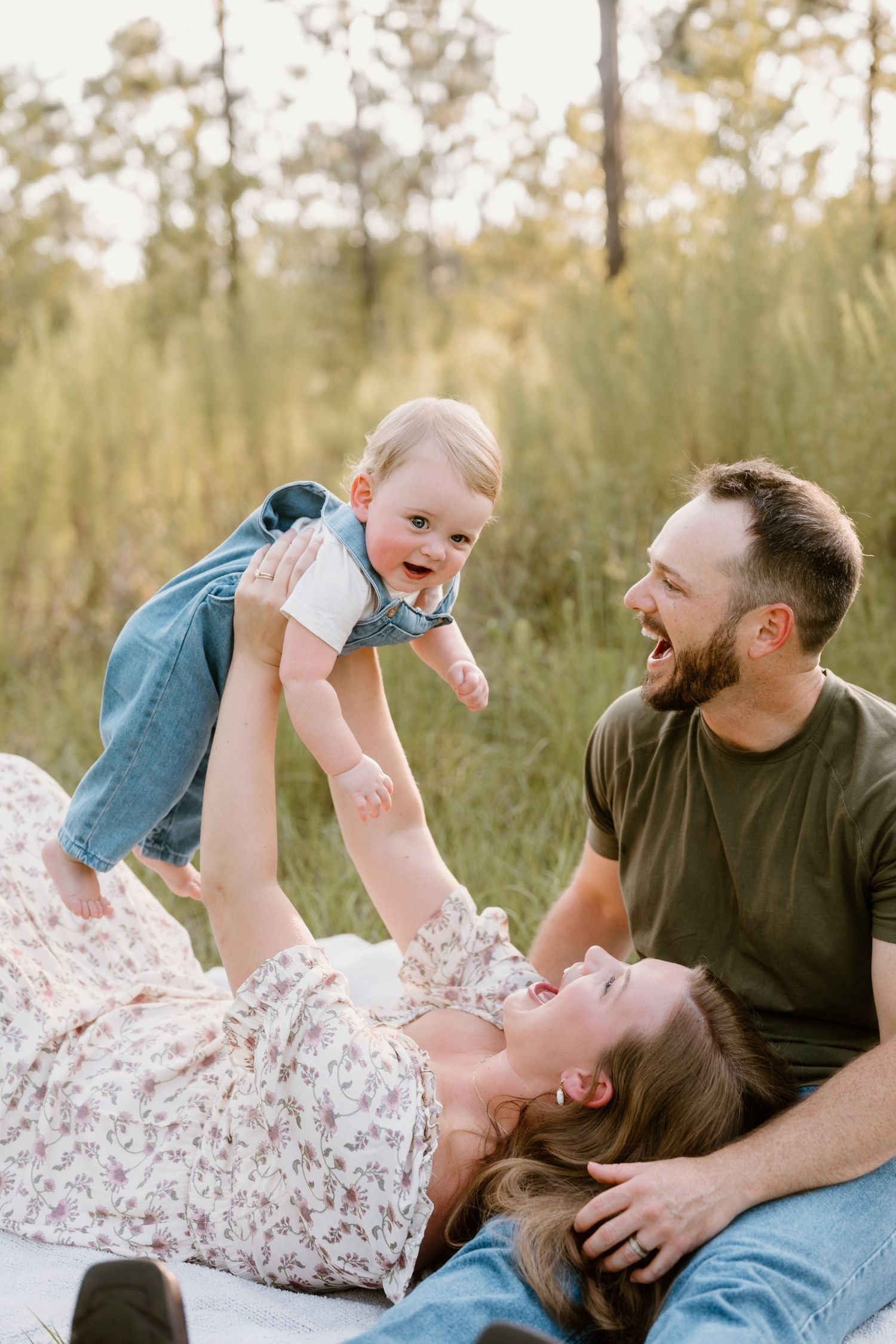 Playful family moment outdoors with baby being lifted in the air.