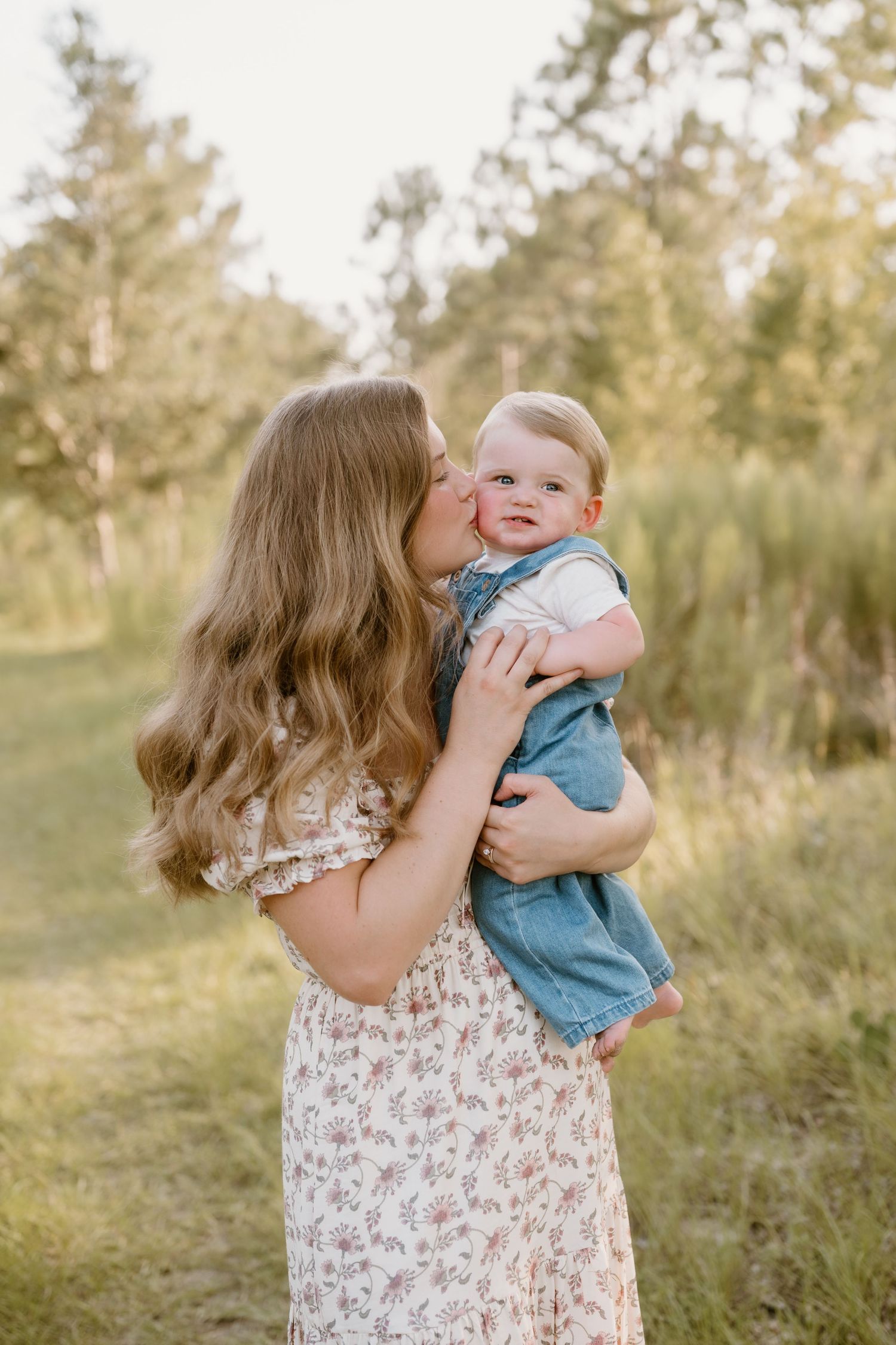 Sweet playful interaction between parent and infant outdoors in natural lighting.