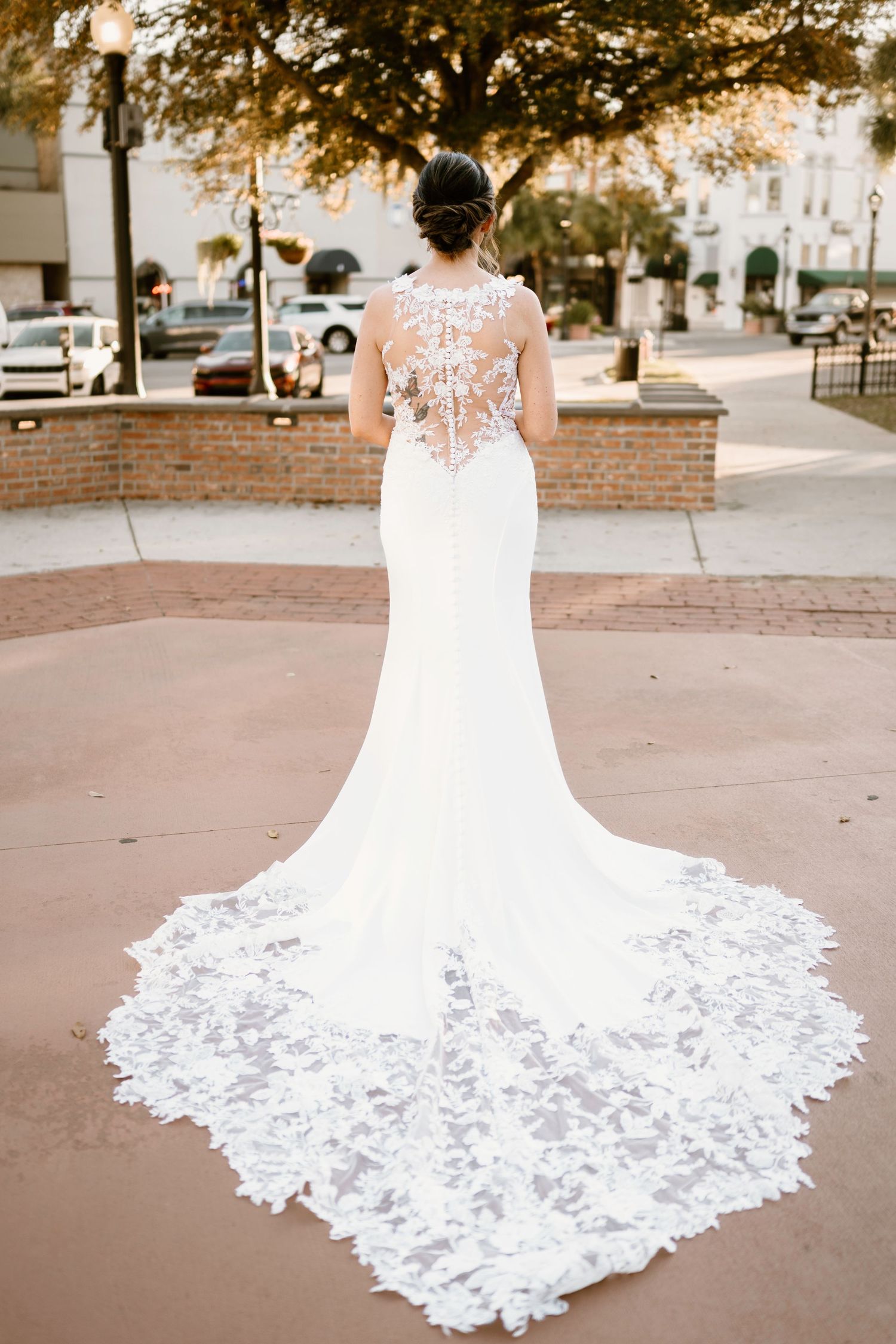 Wedding dress train laid out on brick pavement showing detailed white lace patterns.