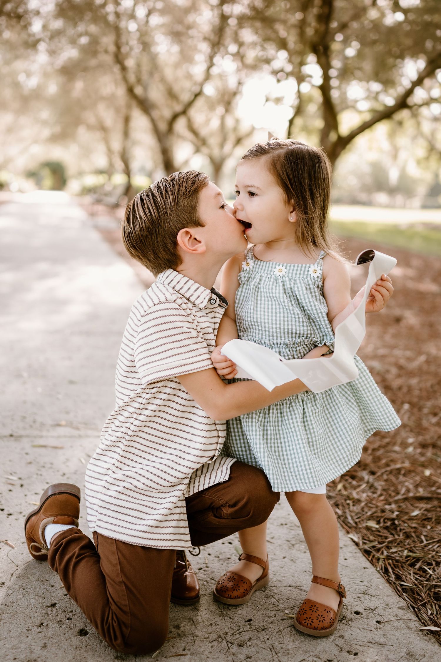 Sweet moment shared between young children under a shady tree.