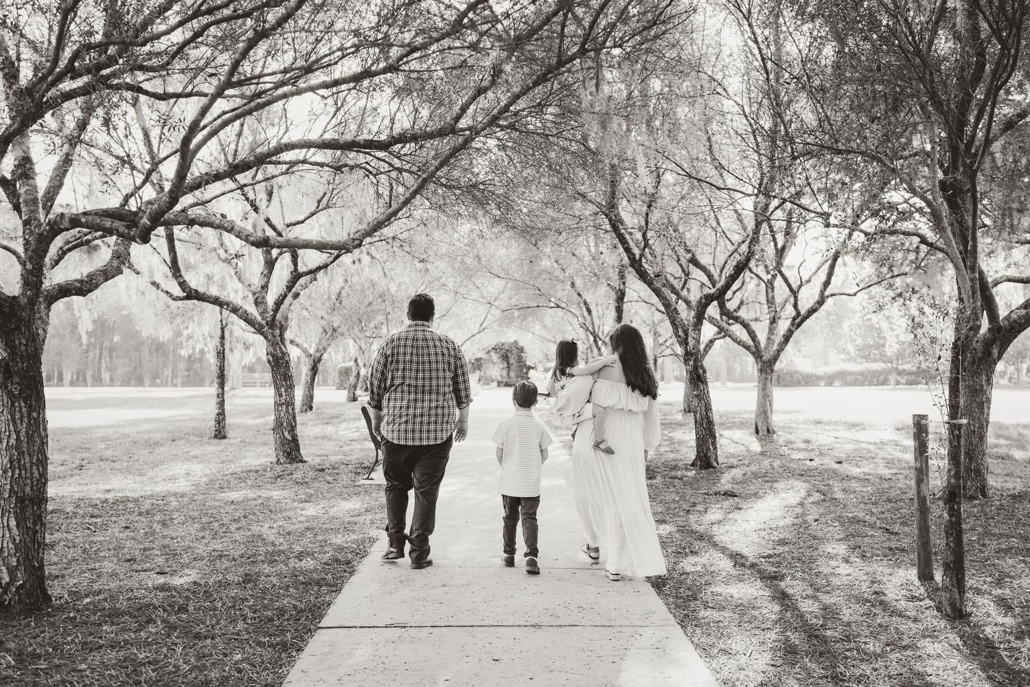Black and white family portrait taken among bare trees in winter landscape.