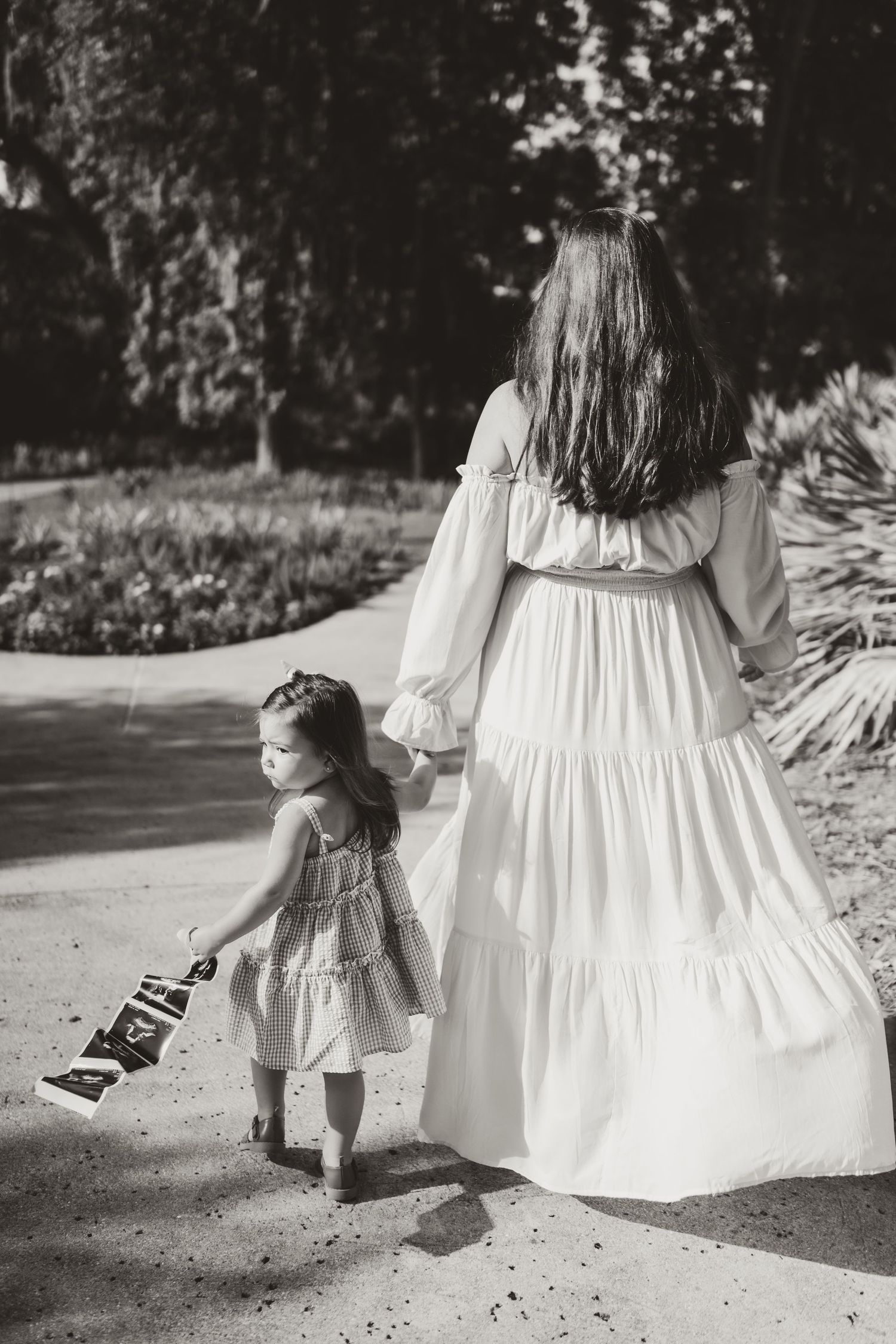 A series of black and white photos showing a child and flowing white dress walking along a path.