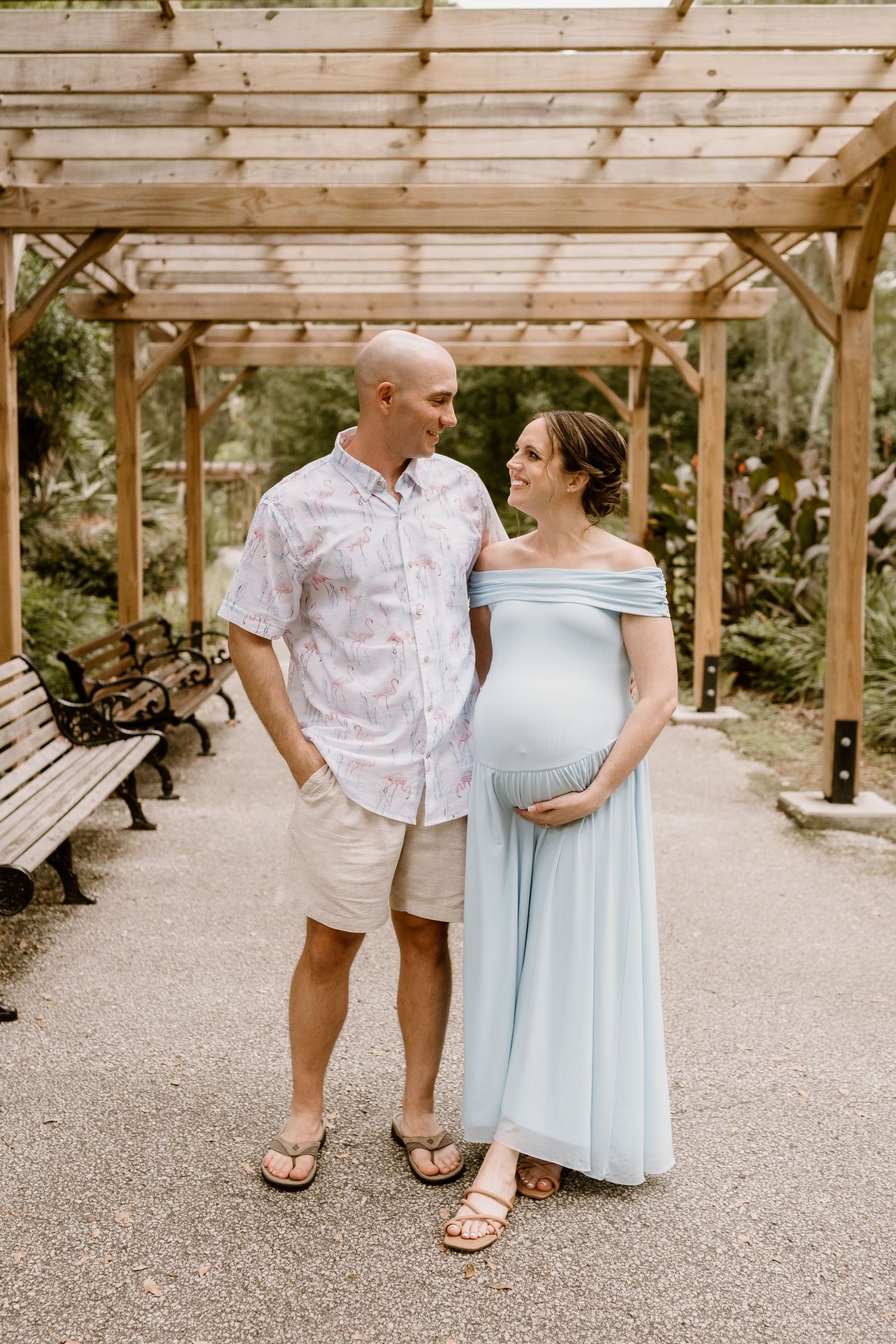 A couple shares intimate moments under a wooden pergola during a photo session.