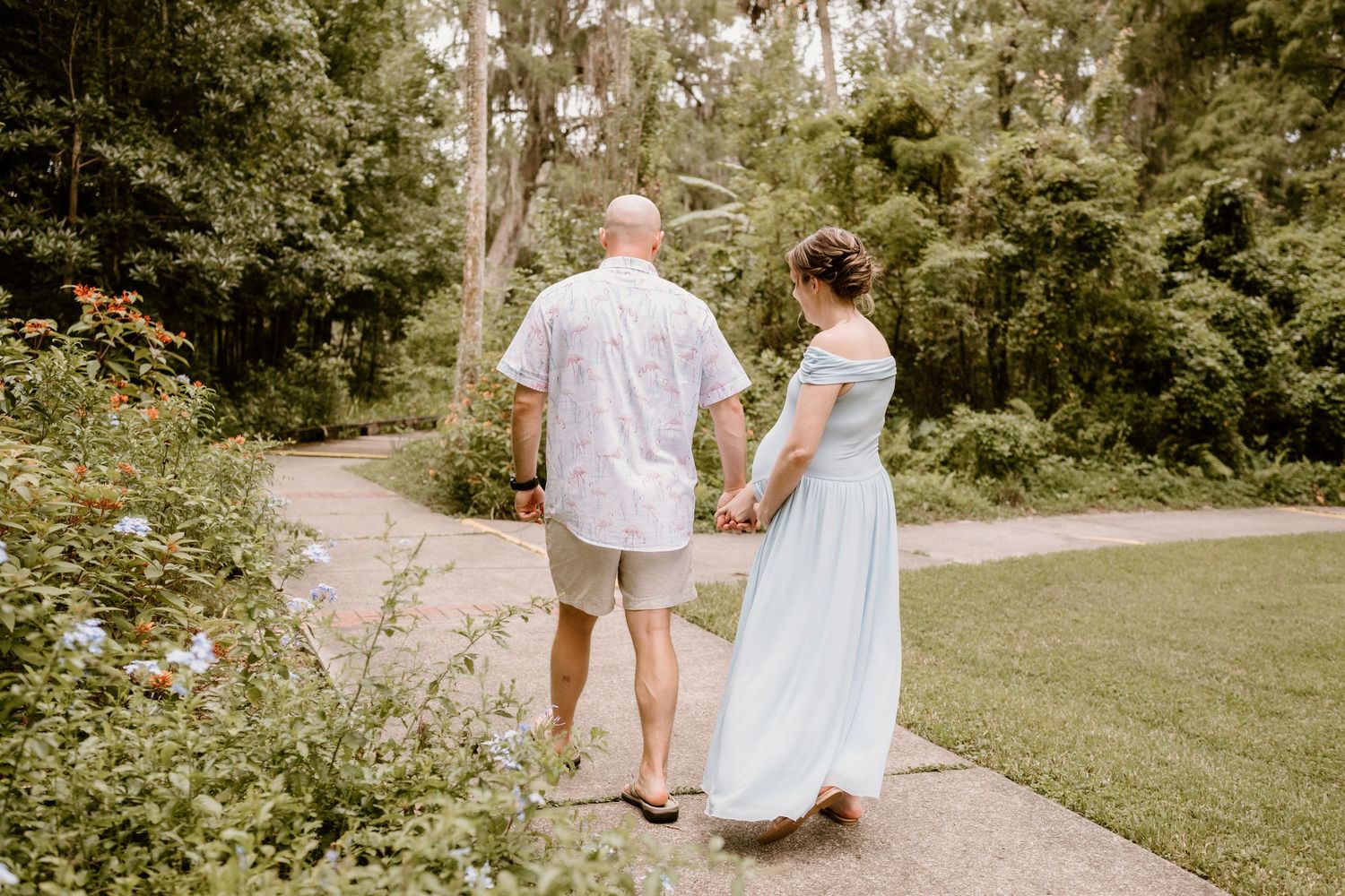 A couple walking along a scenic garden path surrounded by lush greenery.
