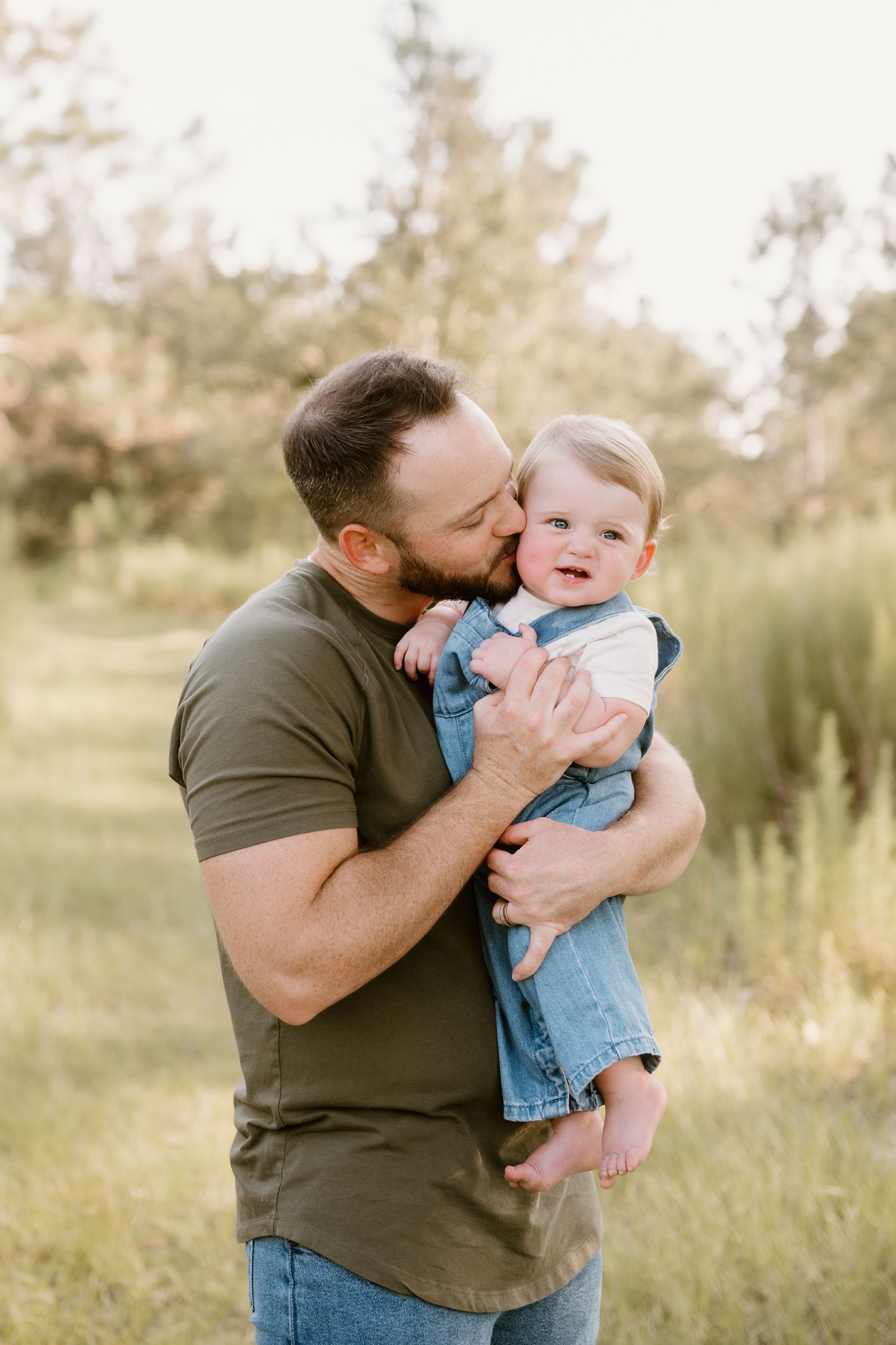 Sweet candid moment between parent and baby in casual wear outdoors.