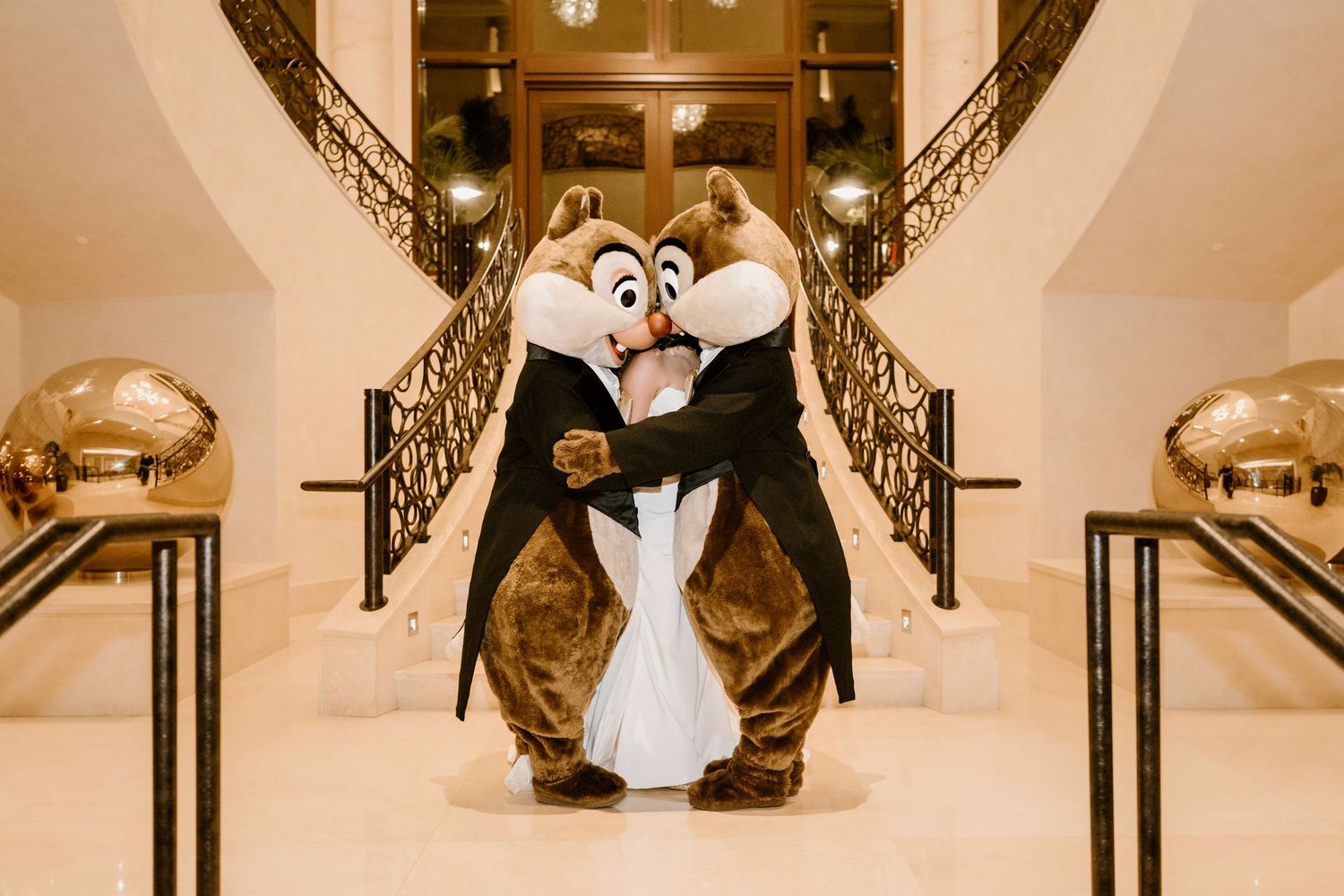 Disney mascots dance on elegant staircase during wedding celebration.