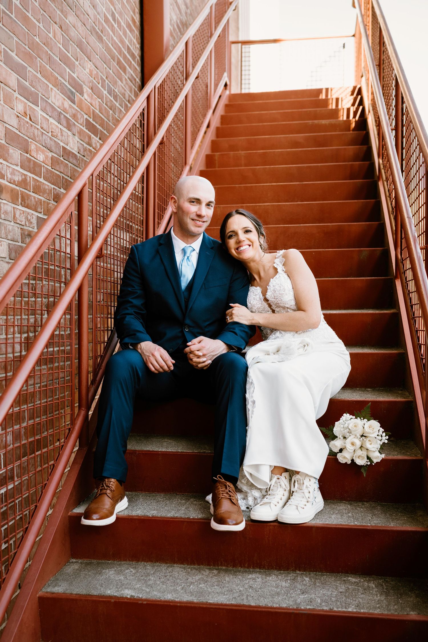 Casual wedding portraits taken on brick staircase showing relaxed moments.