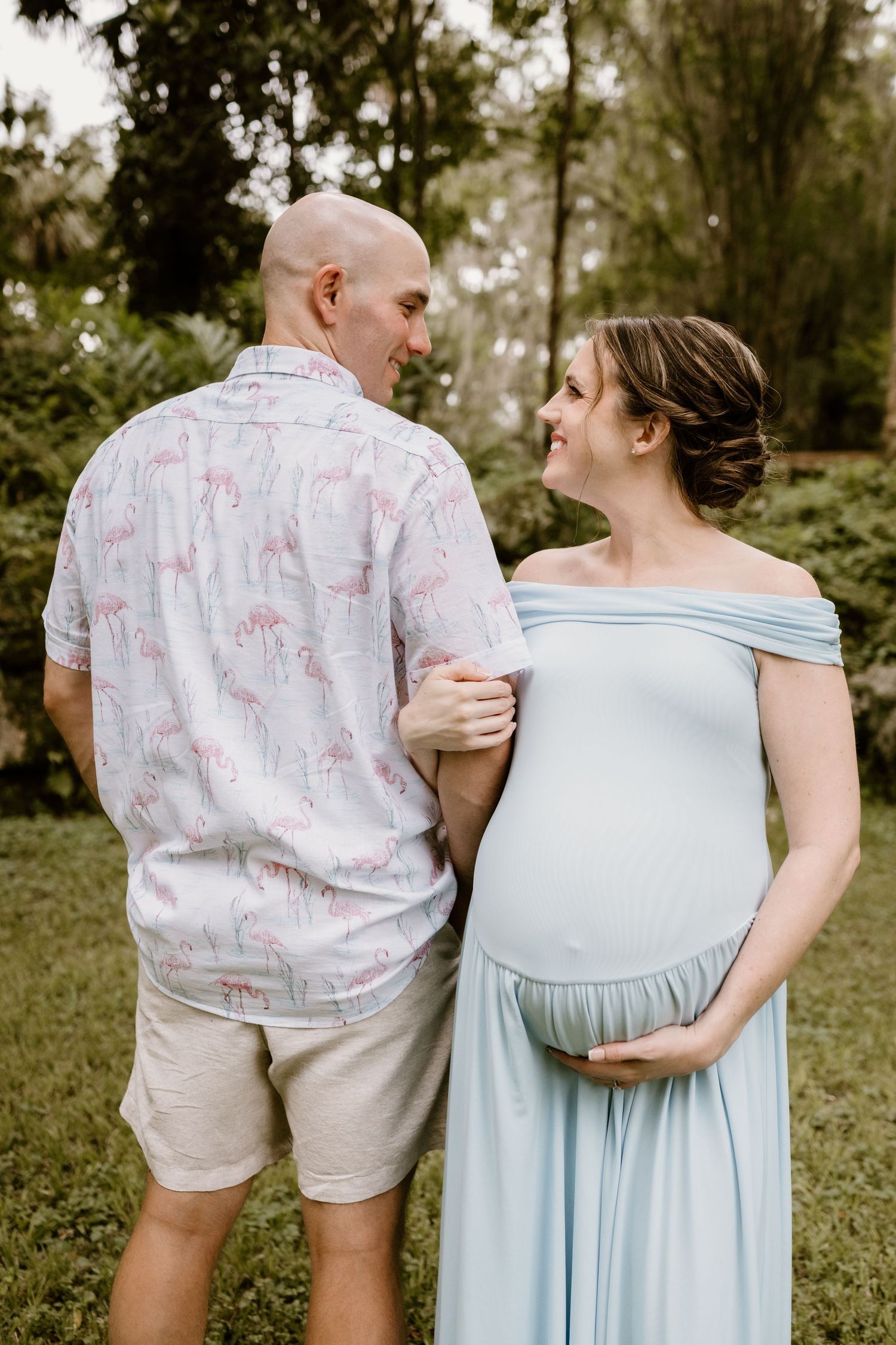 Expectant couple sharing intimate moment in garden setting.