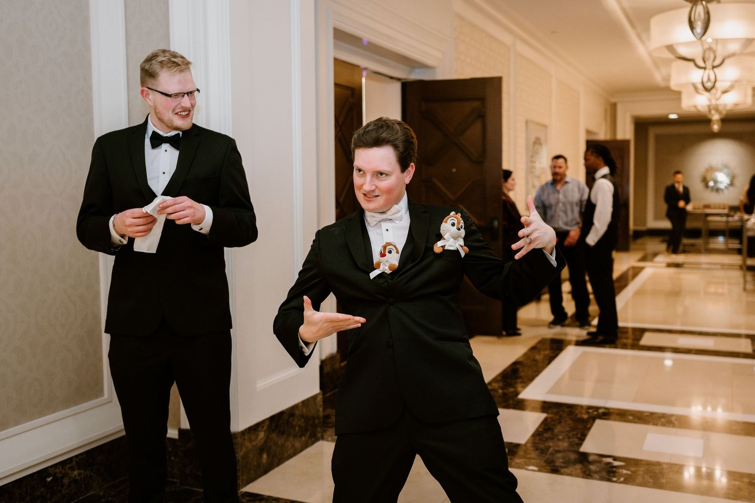 Formal wedding reception with guests and Disney characters in elegant venue hallway.