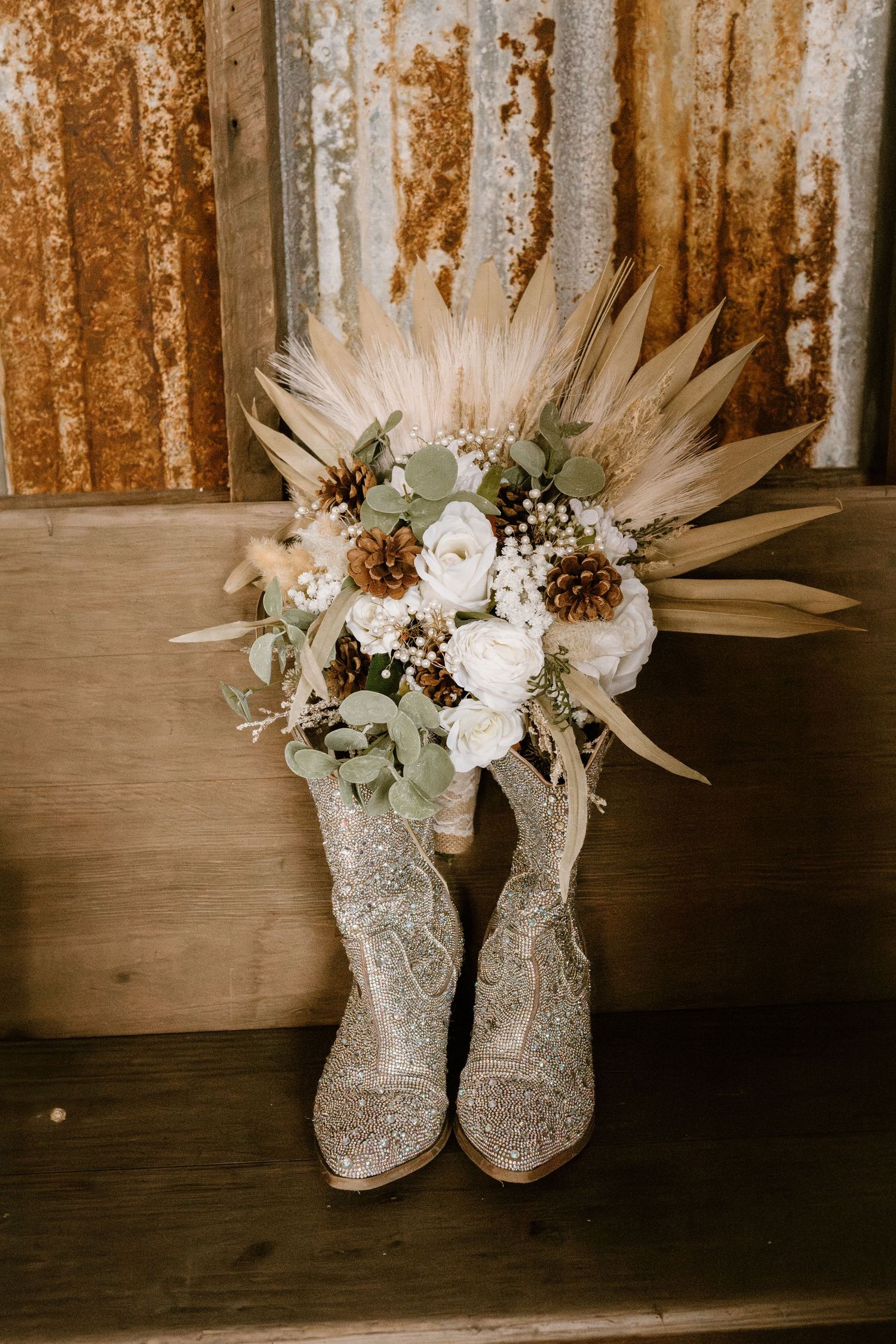 Sparkly silver wedding boots displayed with dried floral arrangements.