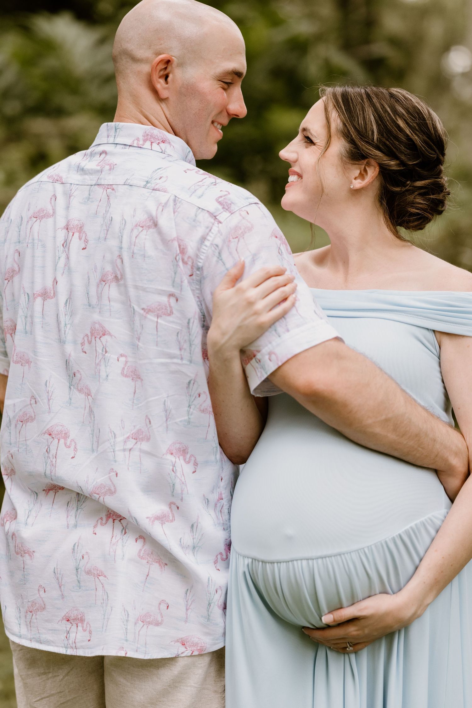 A couple in light blue and floral print embracing tenderly during a romantic outdoor photoshoot.