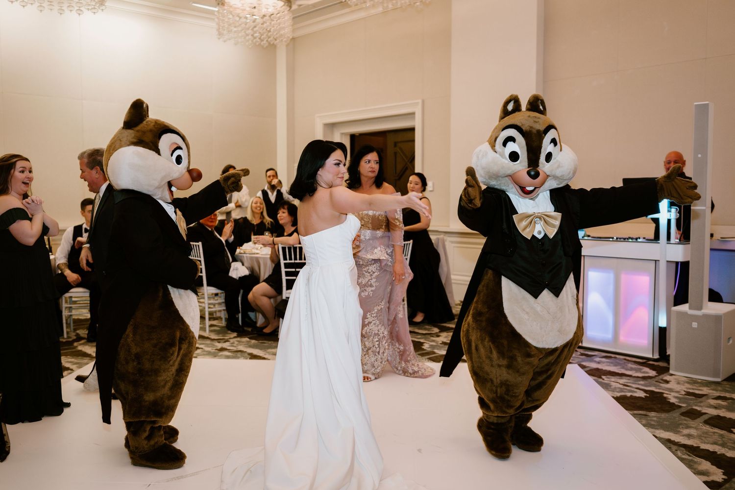 A bride dances with Chip and Dale mascots during her wedding reception.