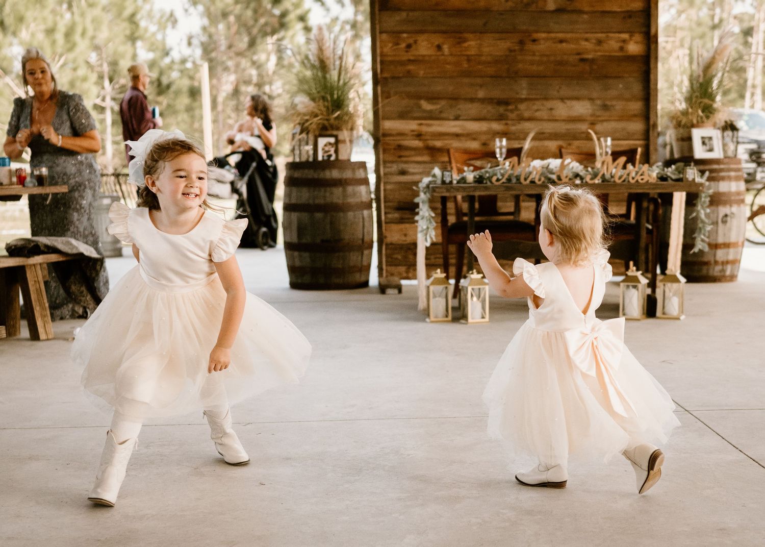 Child in white dress dancing and playing in rustic wooden venue.