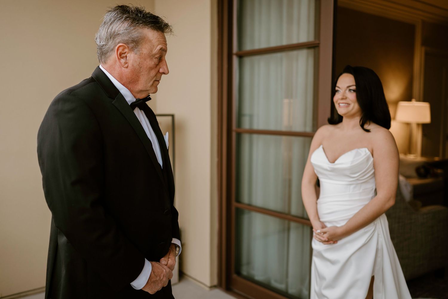 Touching moment of bride and groom meeting before wedding ceremony in elegant indoor setting.