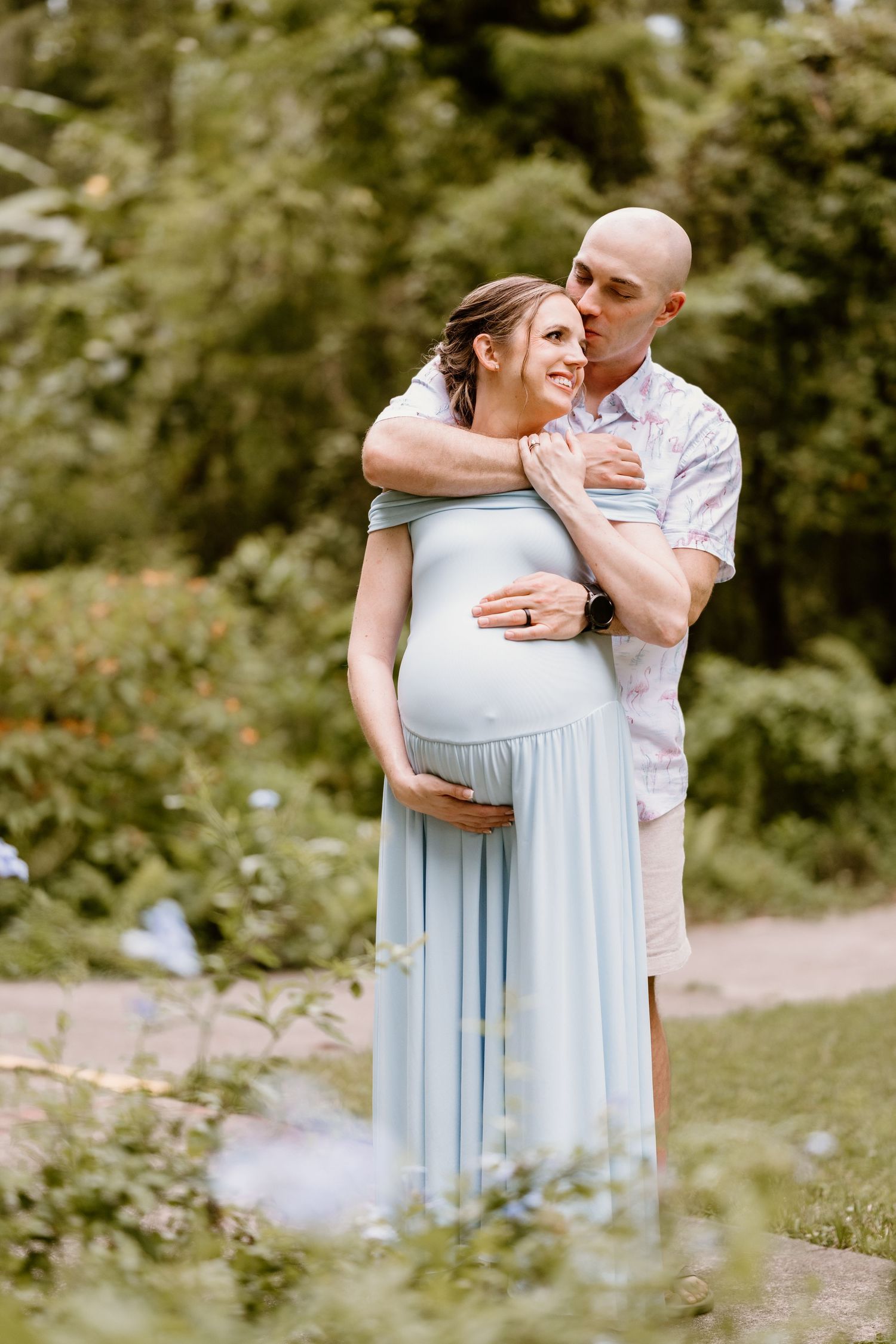 Couple shares intimate moment in blooming meadow with floating bubbles.