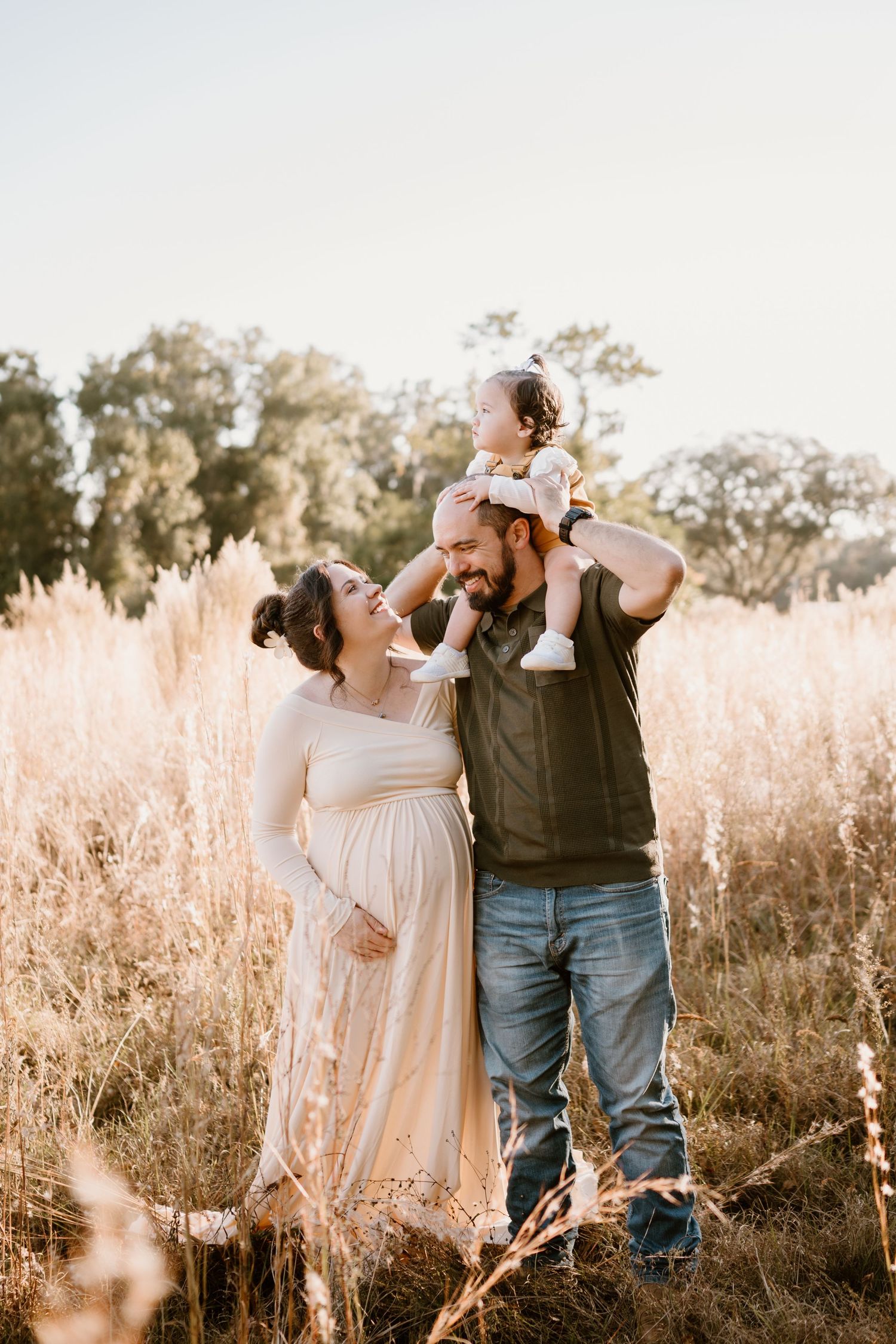 A couple shares romantic moments in a sun-drenched field of tall golden grass during sunset.