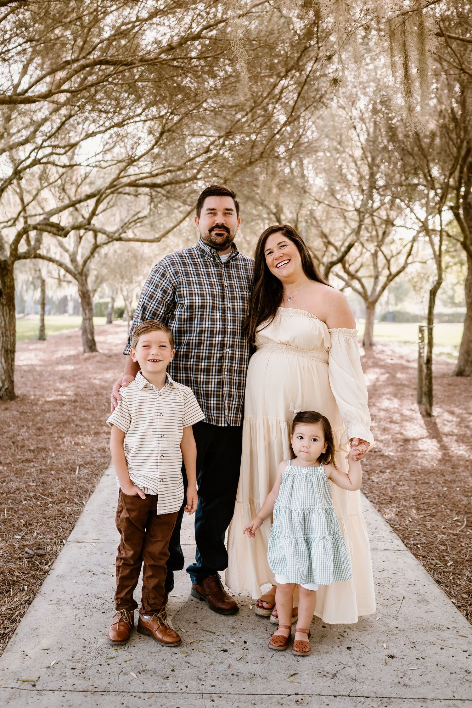 A family portrait session on a scenic path surrounded by trees.