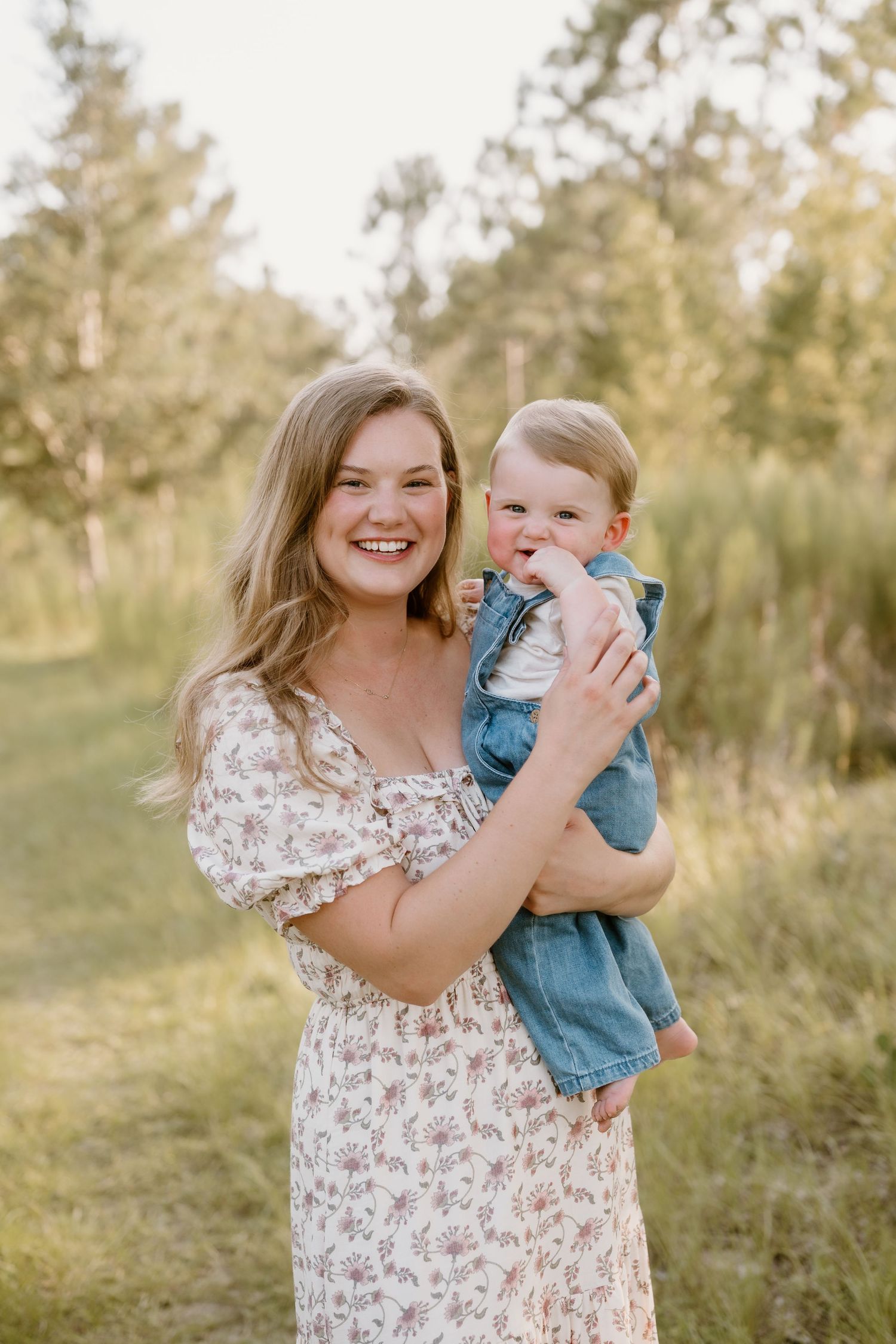 A family portrait in a sunlit meadow with a floral dress and denim overalls.