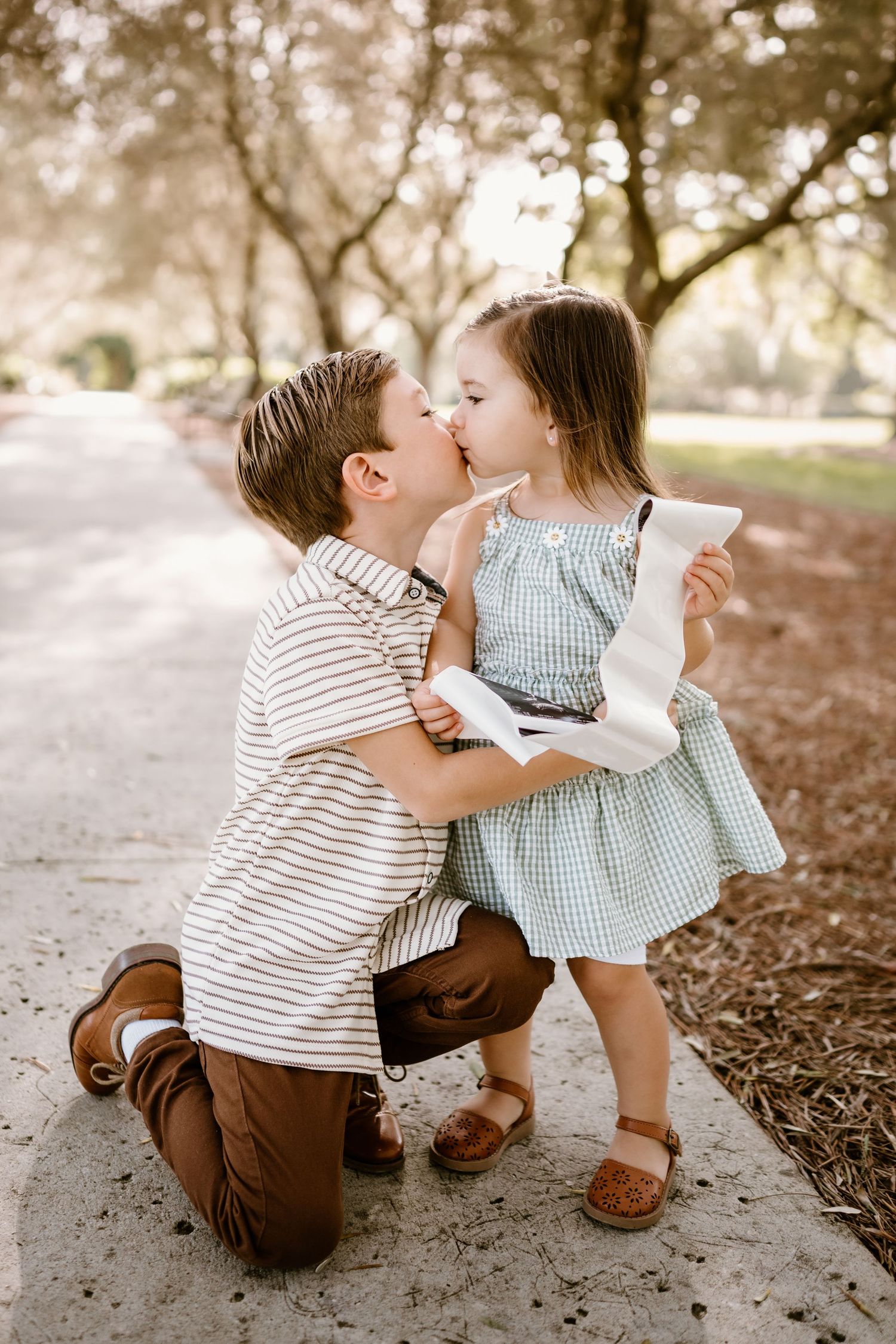 Two young children sharing a sweet moment while sitting on the ground.
