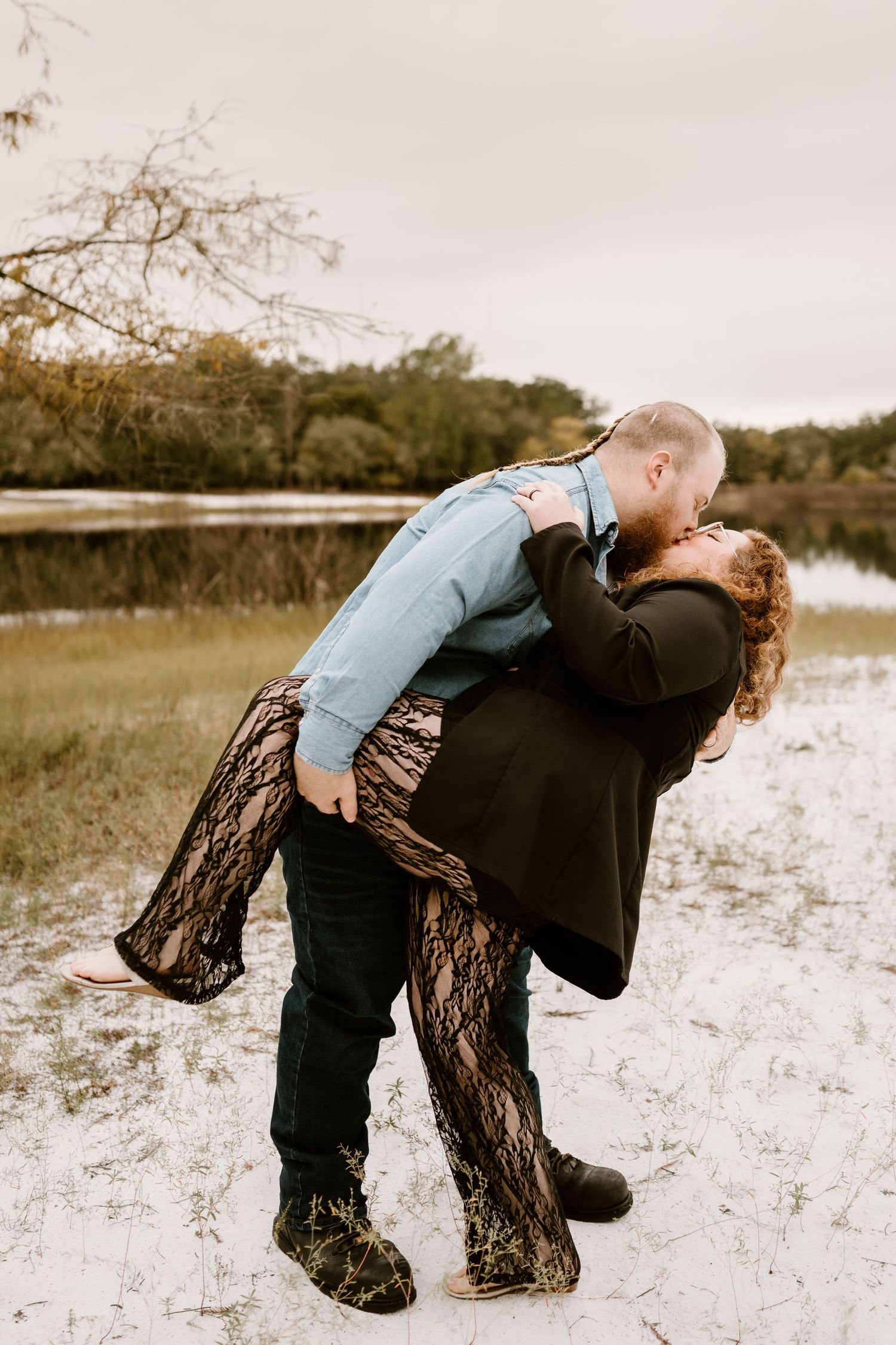 Couple posing dramatically in a rustic outdoor setting with vintage aesthetic.