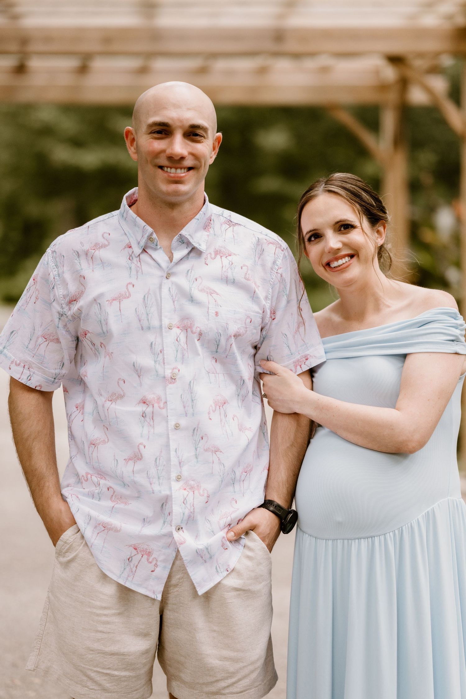 A couple poses together outdoors wearing coordinated light blue and floral print outfits.