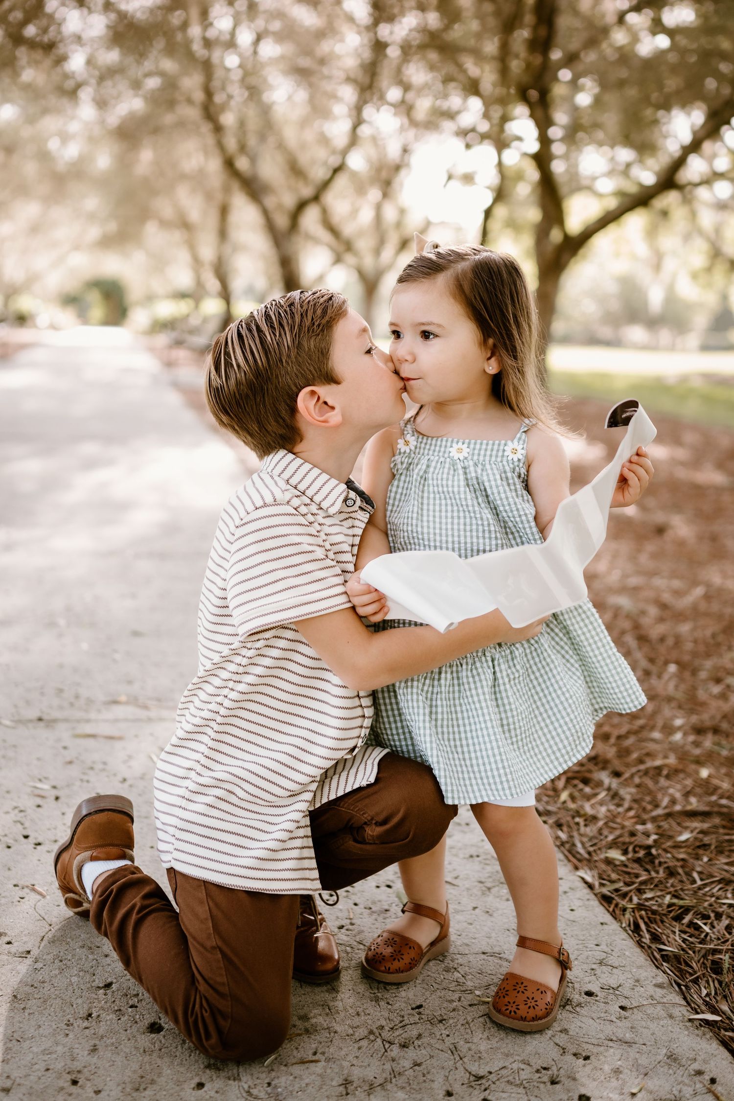 Sweet candid moments between two young children playing outdoors in casual attire.