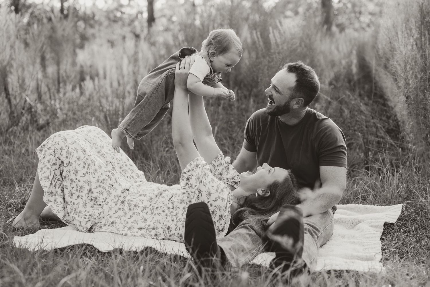 Black and white photo series of a couple lying on a blanket in a grassy field showing playful interaction.