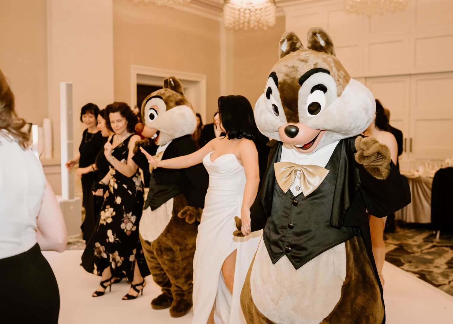 Disney mascot characters entertain guests during a wedding reception in an elegant venue.