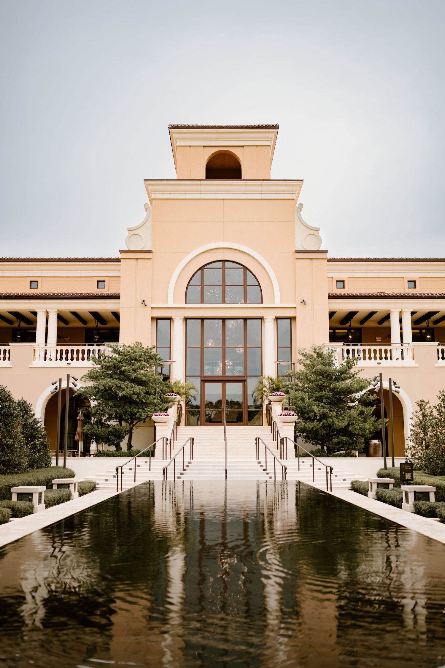 Luxurious Mediterranean-style venue with reflecting pool and grand staircase entrance.