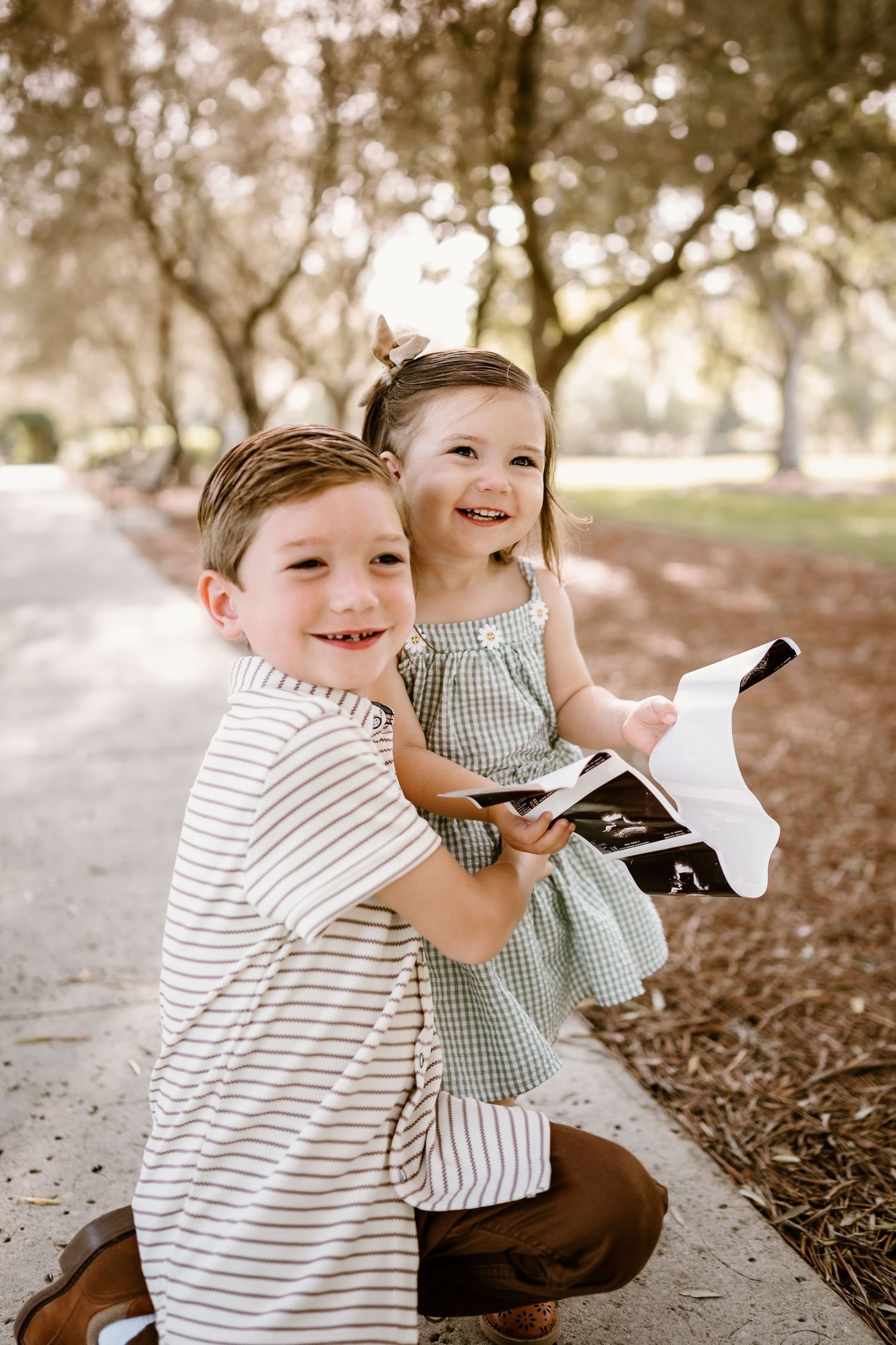 Two children sharing joyful laughter while sitting on autumn ground.