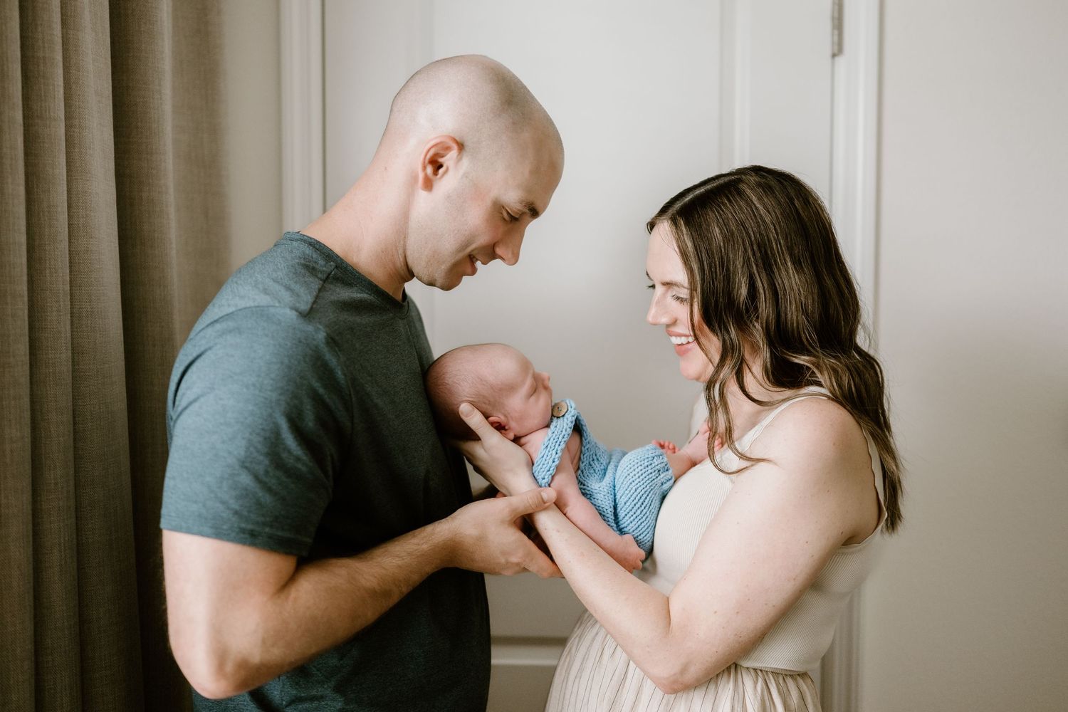 Indoor lifestyle photos of new parents sharing intimate moments with their baby.
