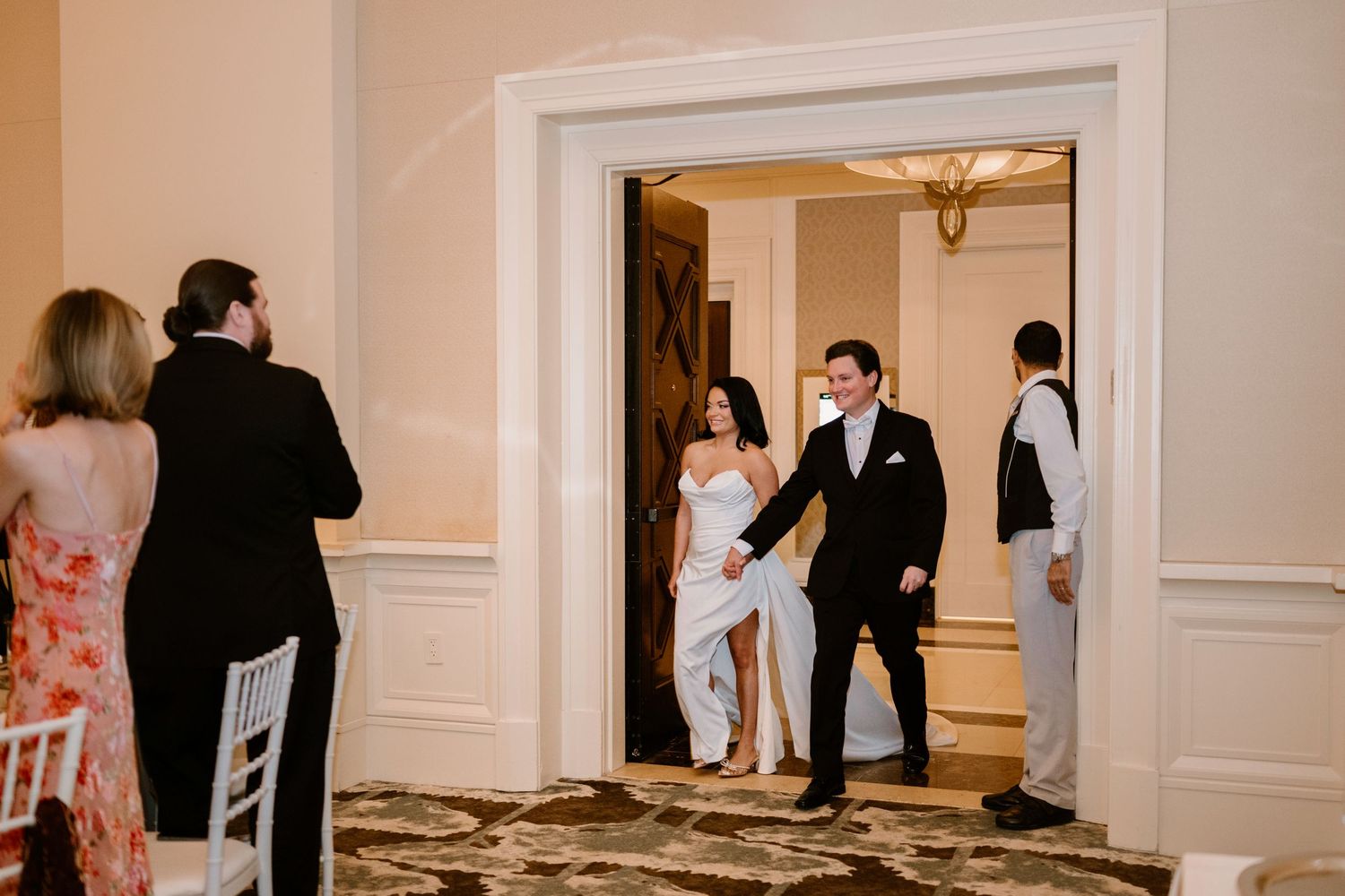 Wedding guests mingling in an elegant cream-colored reception hallway.