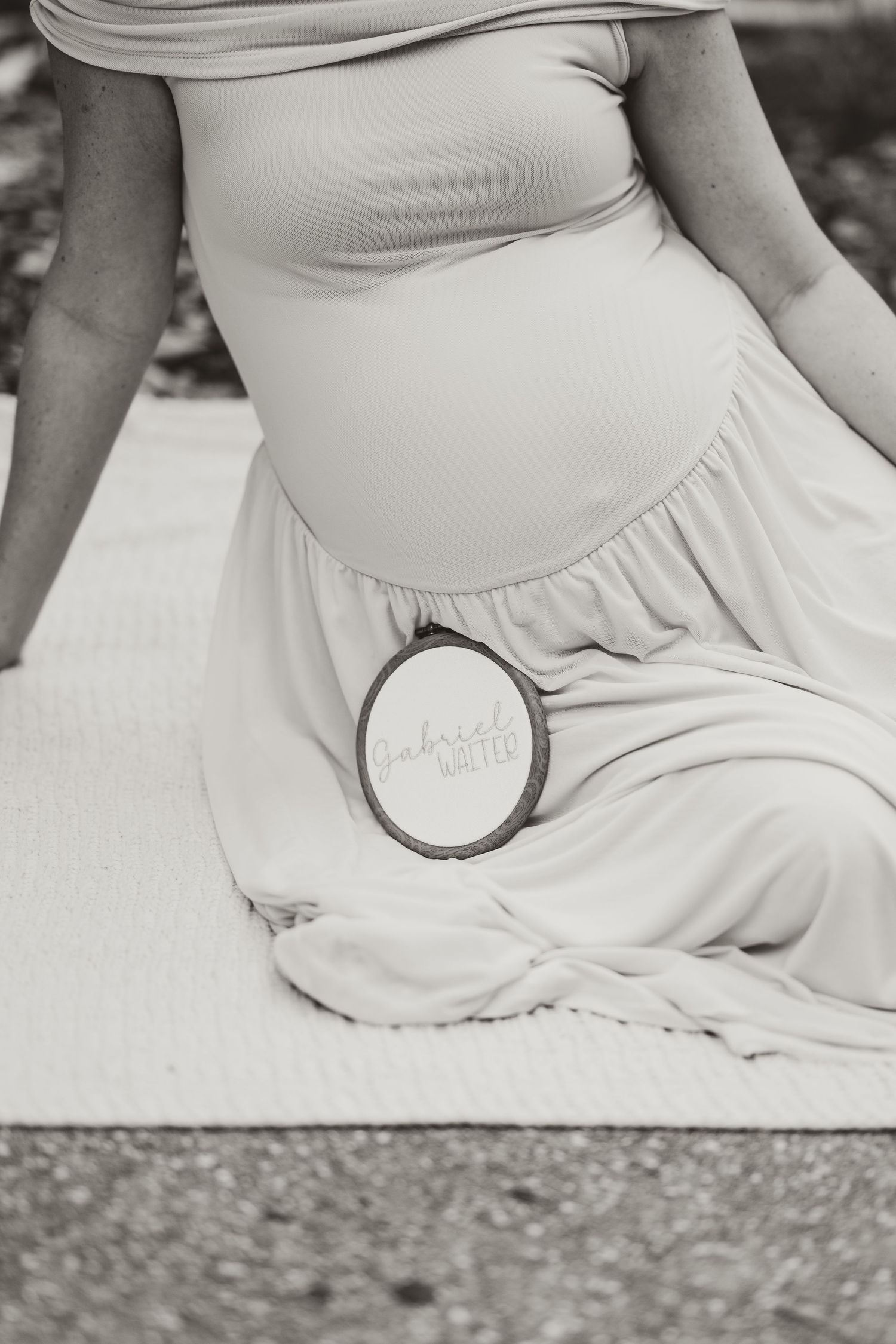Close-up view of a white maternity dress against a textured background.
