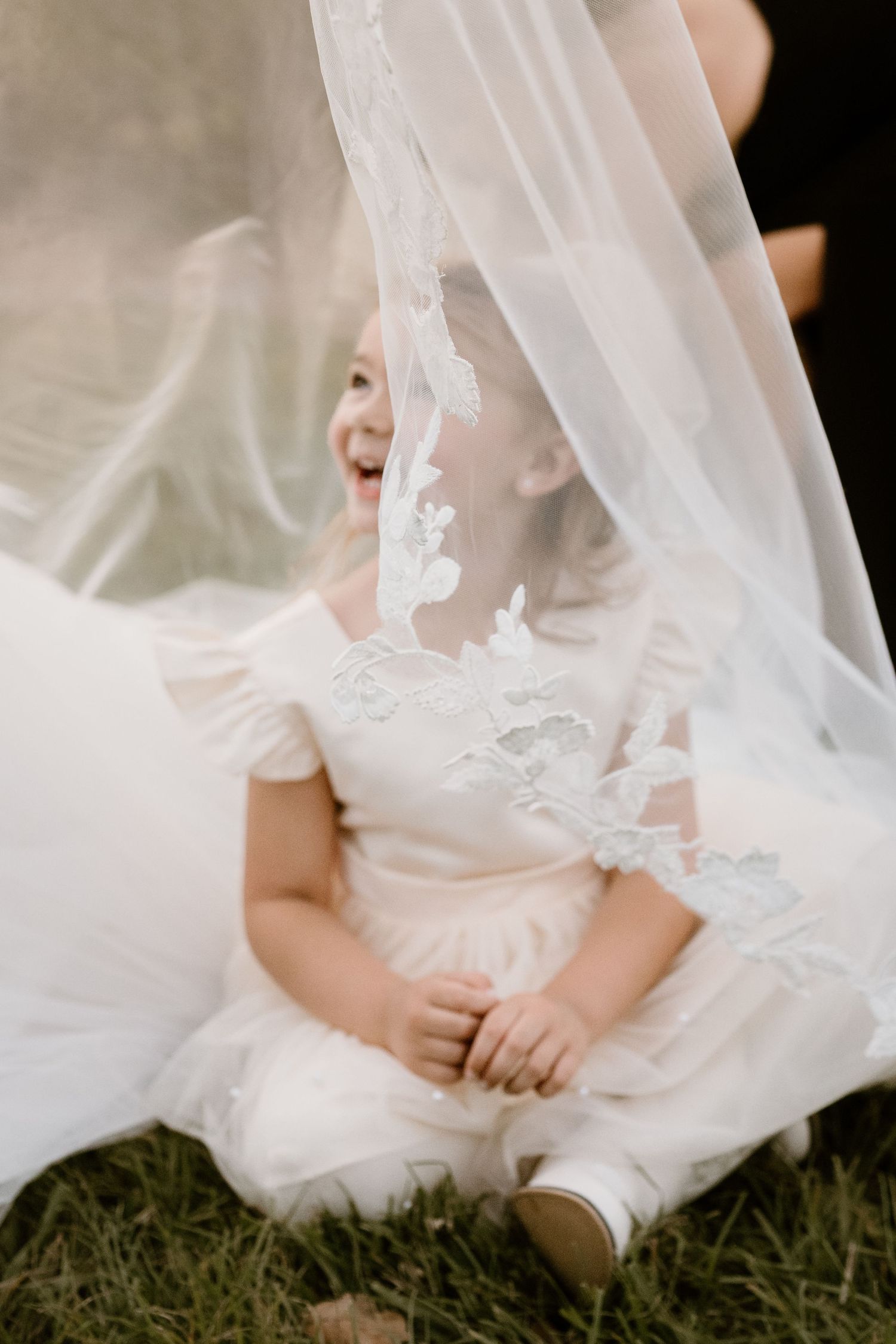 Close-up detail of delicate white lace wedding veil against grass.
